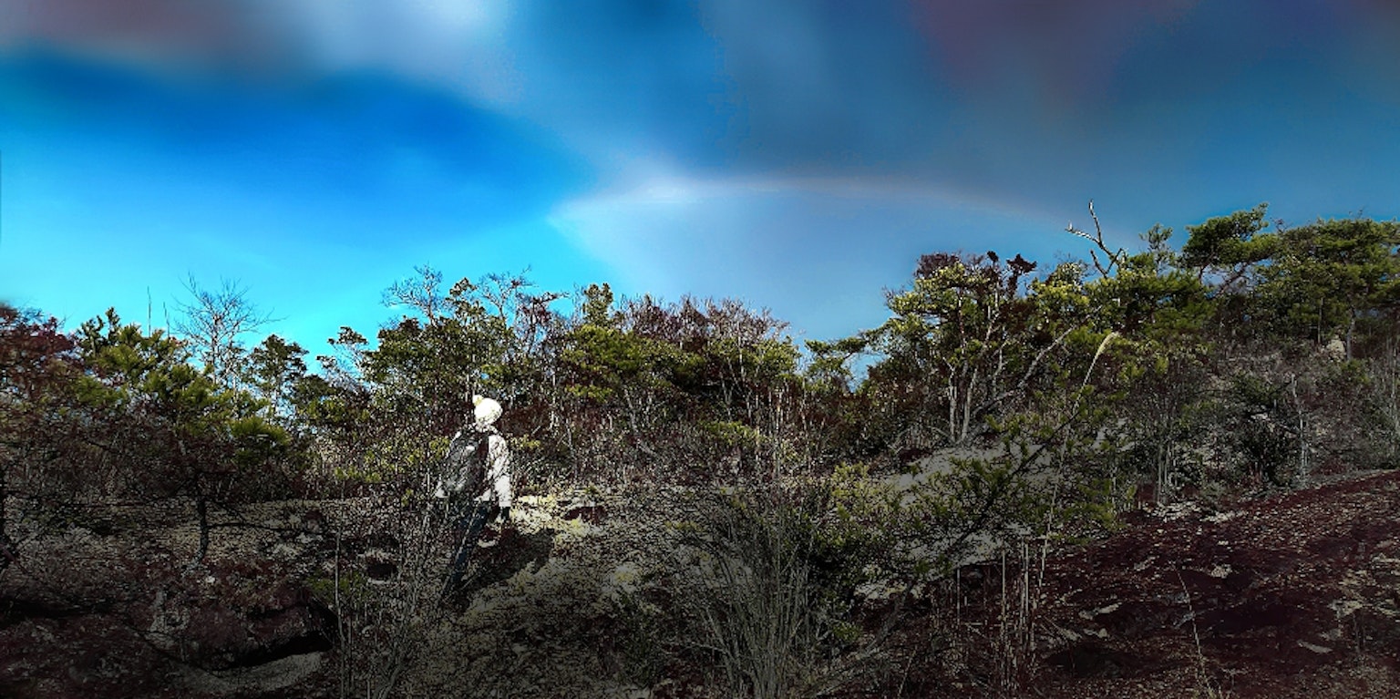 A person standing in a scenic landscape with a beautiful sky and a rainbow