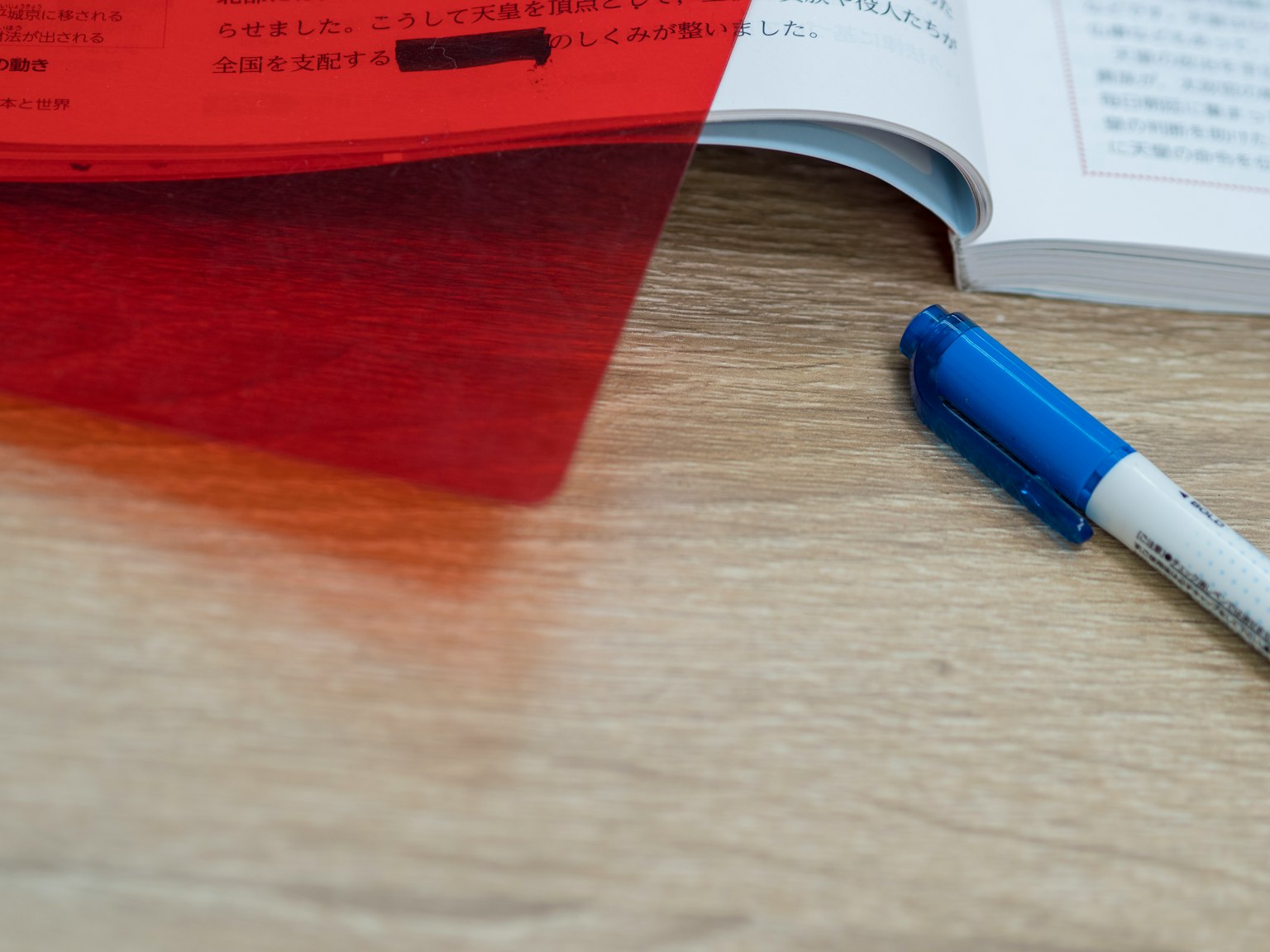 Red clear file and blue pen on a wooden table