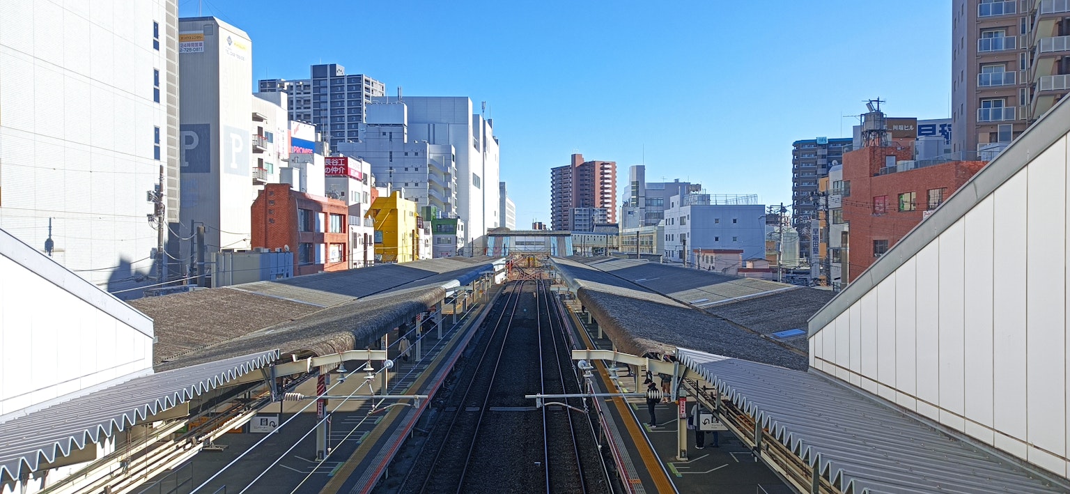 Stadtbahnhof mit erhöhten Gleisen unter klarem blauen Himmel