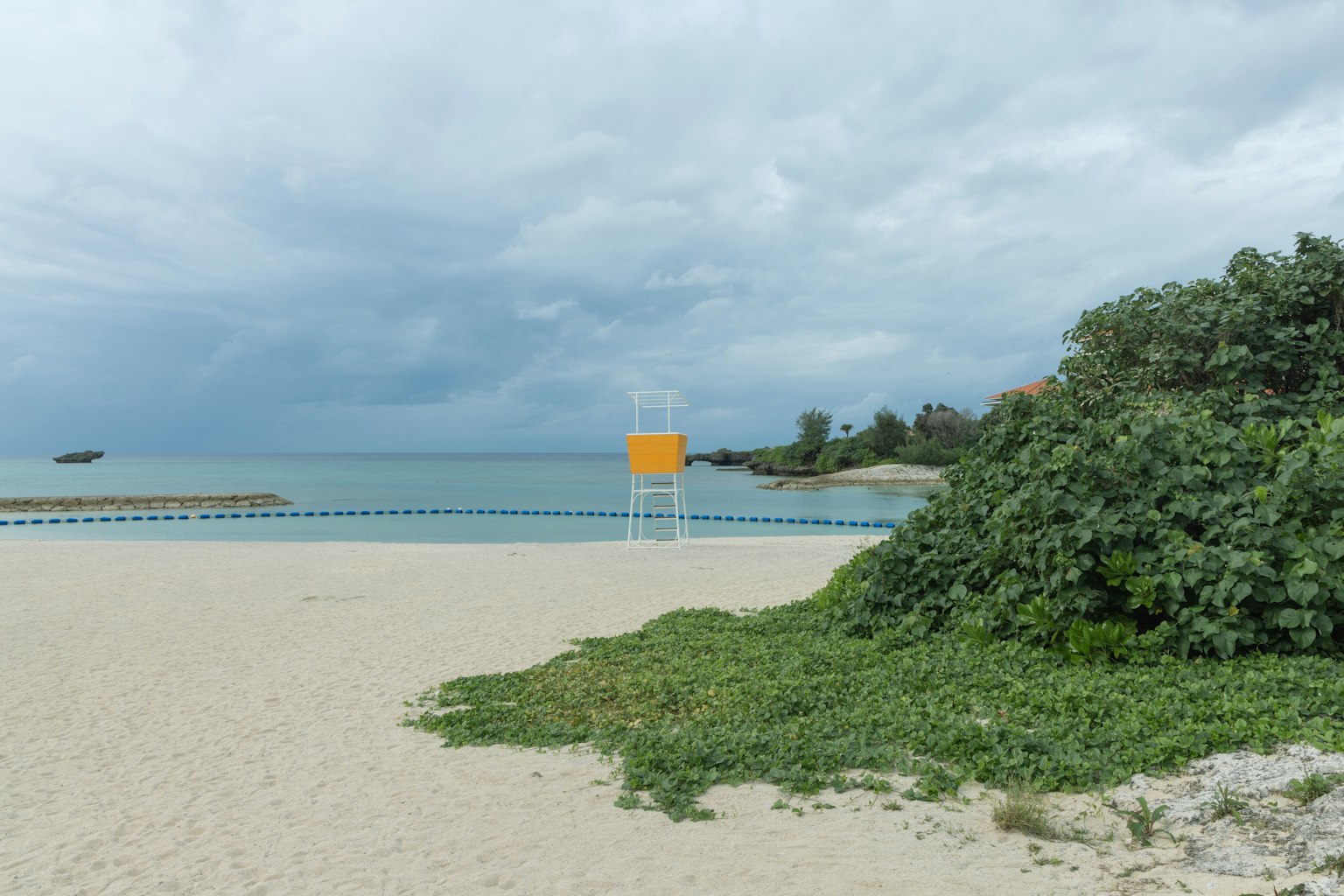 Scena di spiaggia con una torre di salvataggio gialla e mare calmo