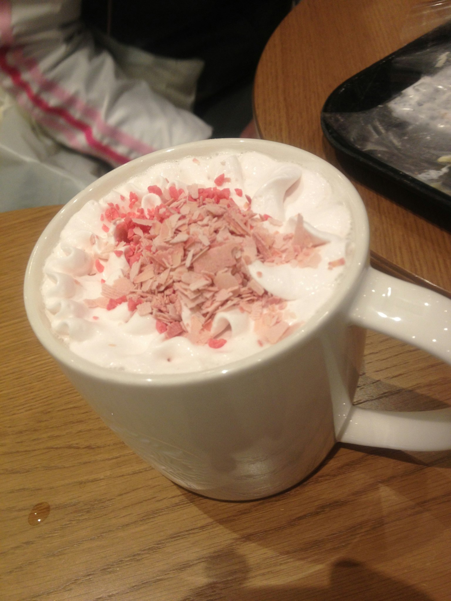 Tazza di bevanda calda guarnita con panna montata e scaglie rosa