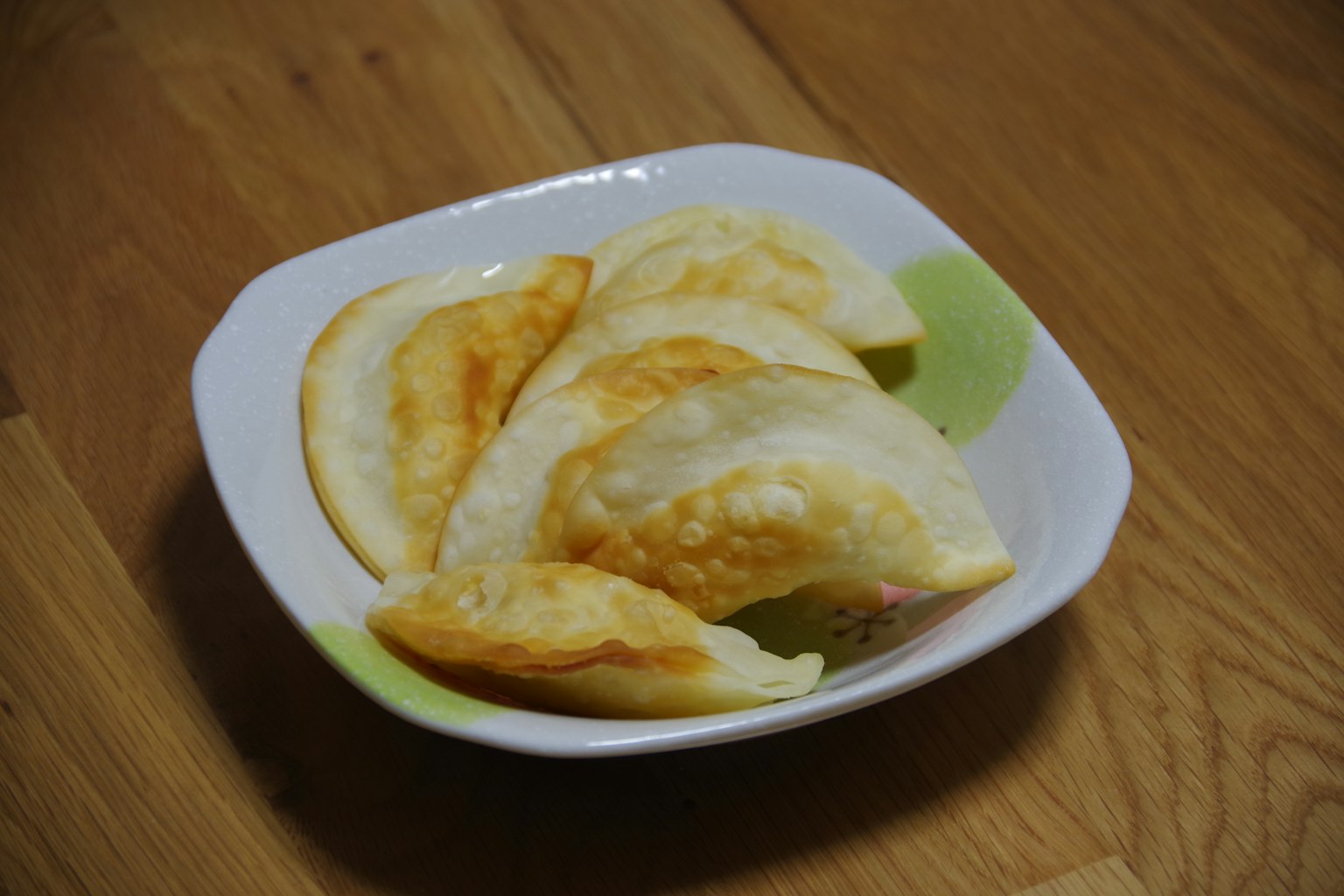 Un piatto di ravioli fritti dorati disposti in un piatto bianco