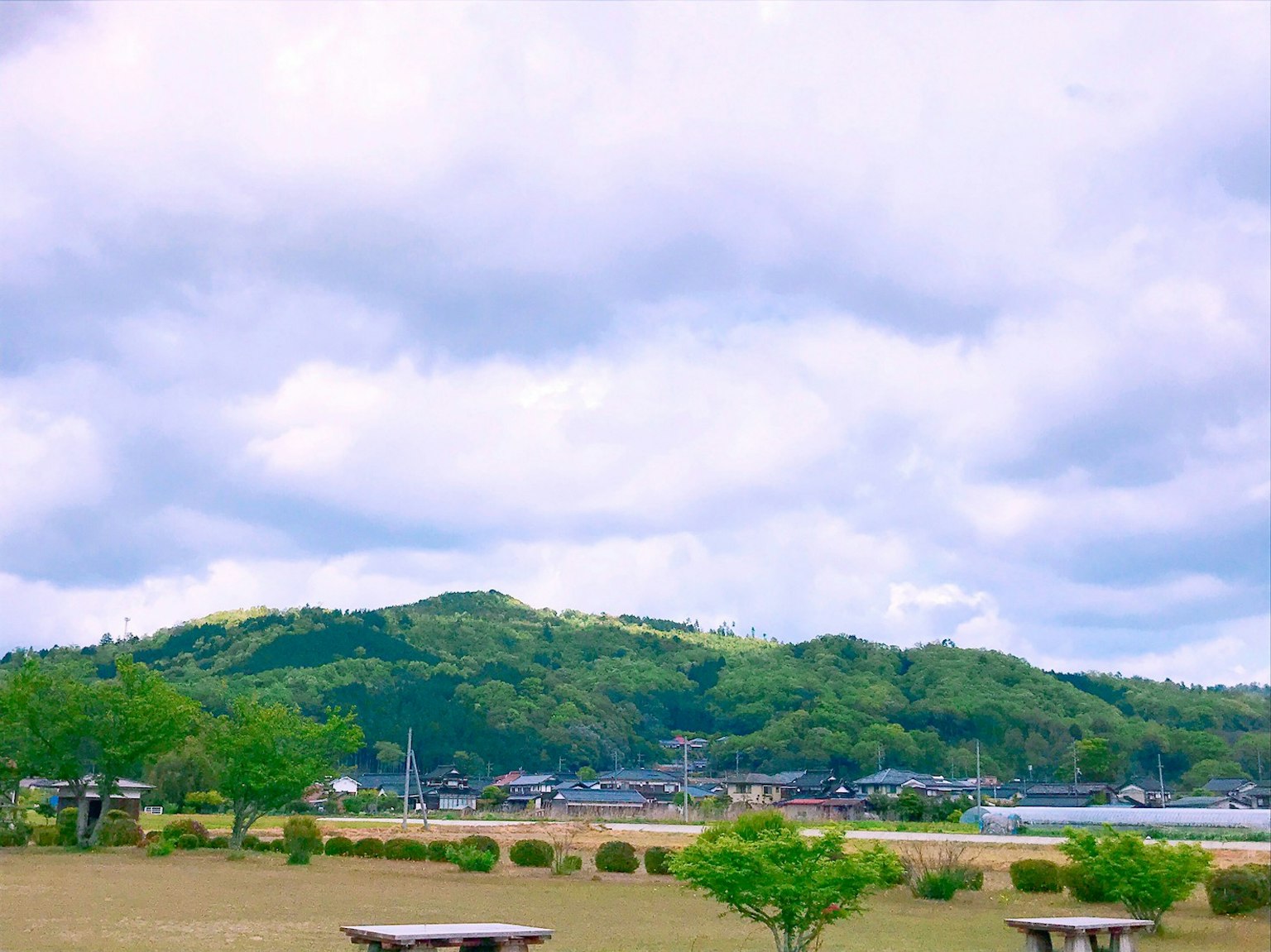 蓝天与云下的绿色山丘和宁静水边的风景
