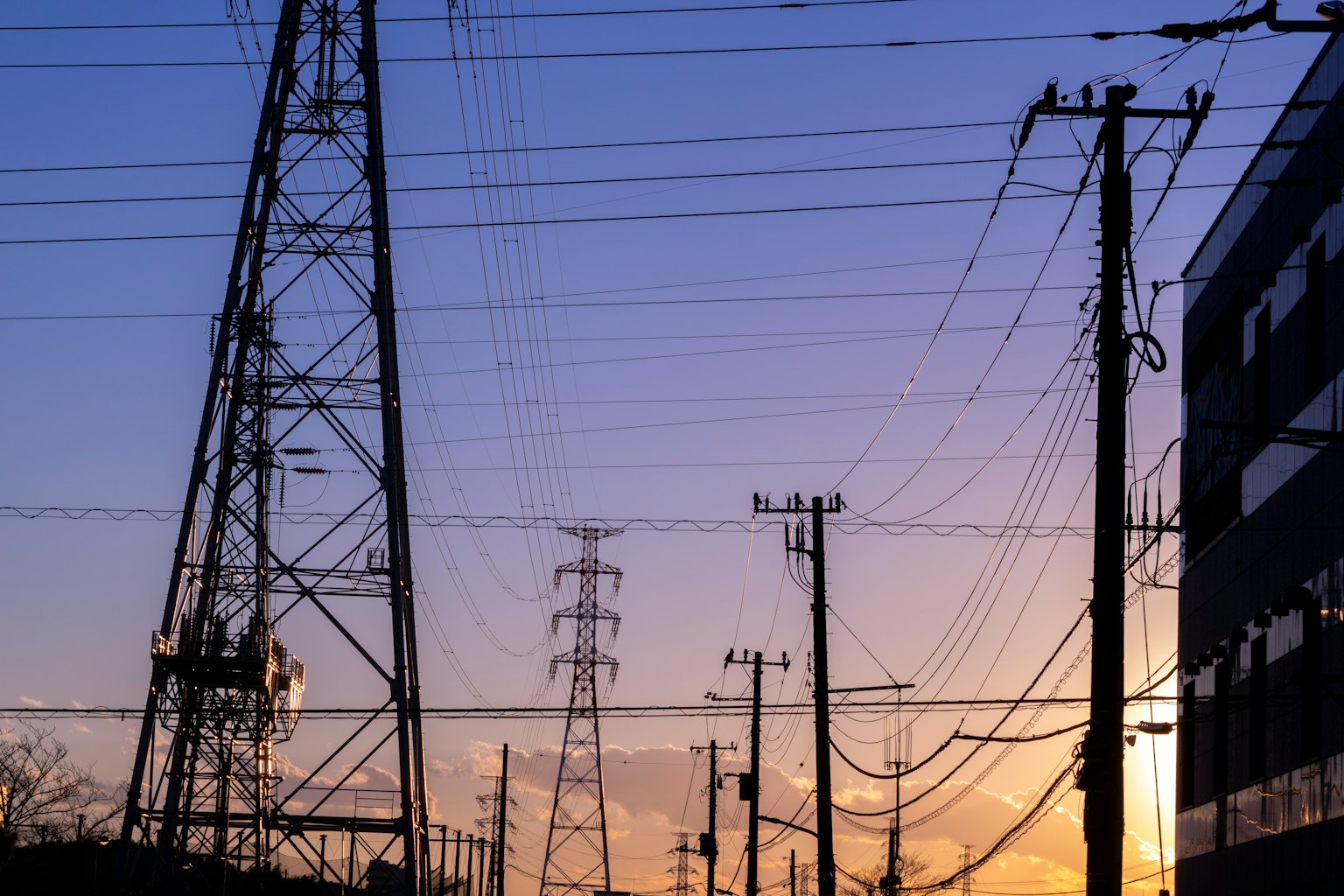 Silhouette de lignes électriques et de poteaux au coucher du soleil