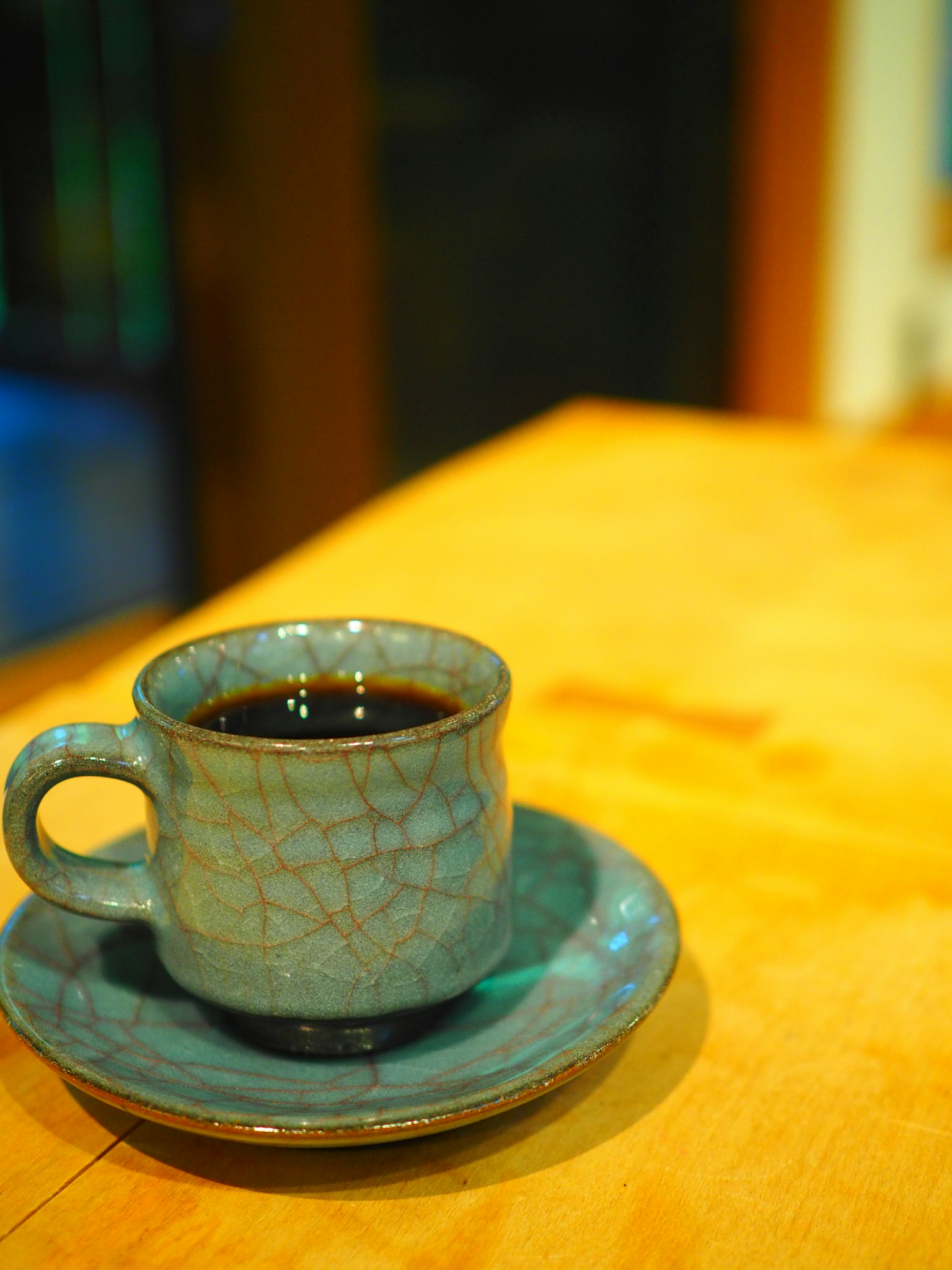 ถ้วยกาแฟเซรามิกสีน้ำเงินและจานวางอยู่บนโต๊ะไม้