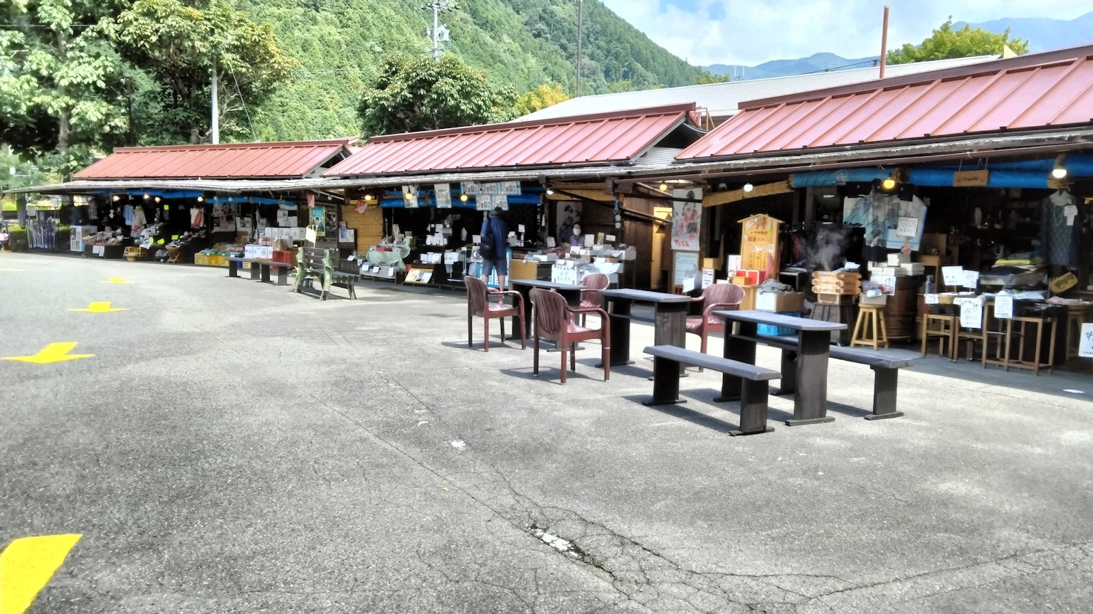 Pasar luar ruangan dengan toko dan meja dikelilingi pegunungan