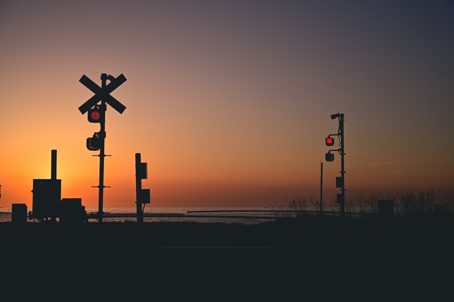 Silhouette eines Bahnübergangs und Signale bei Sonnenuntergang