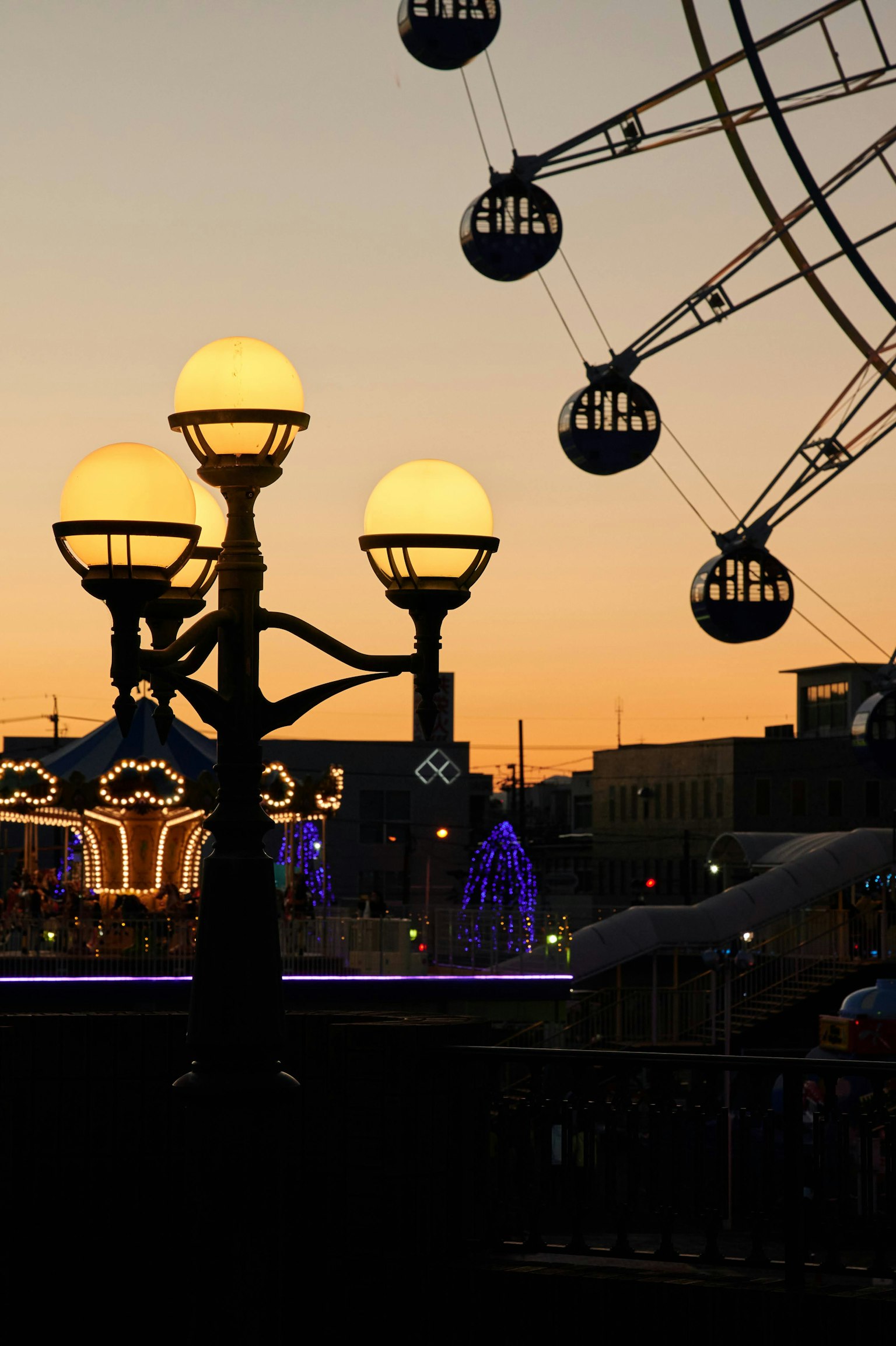Amusement park scene with a sunset and a ferris wheel