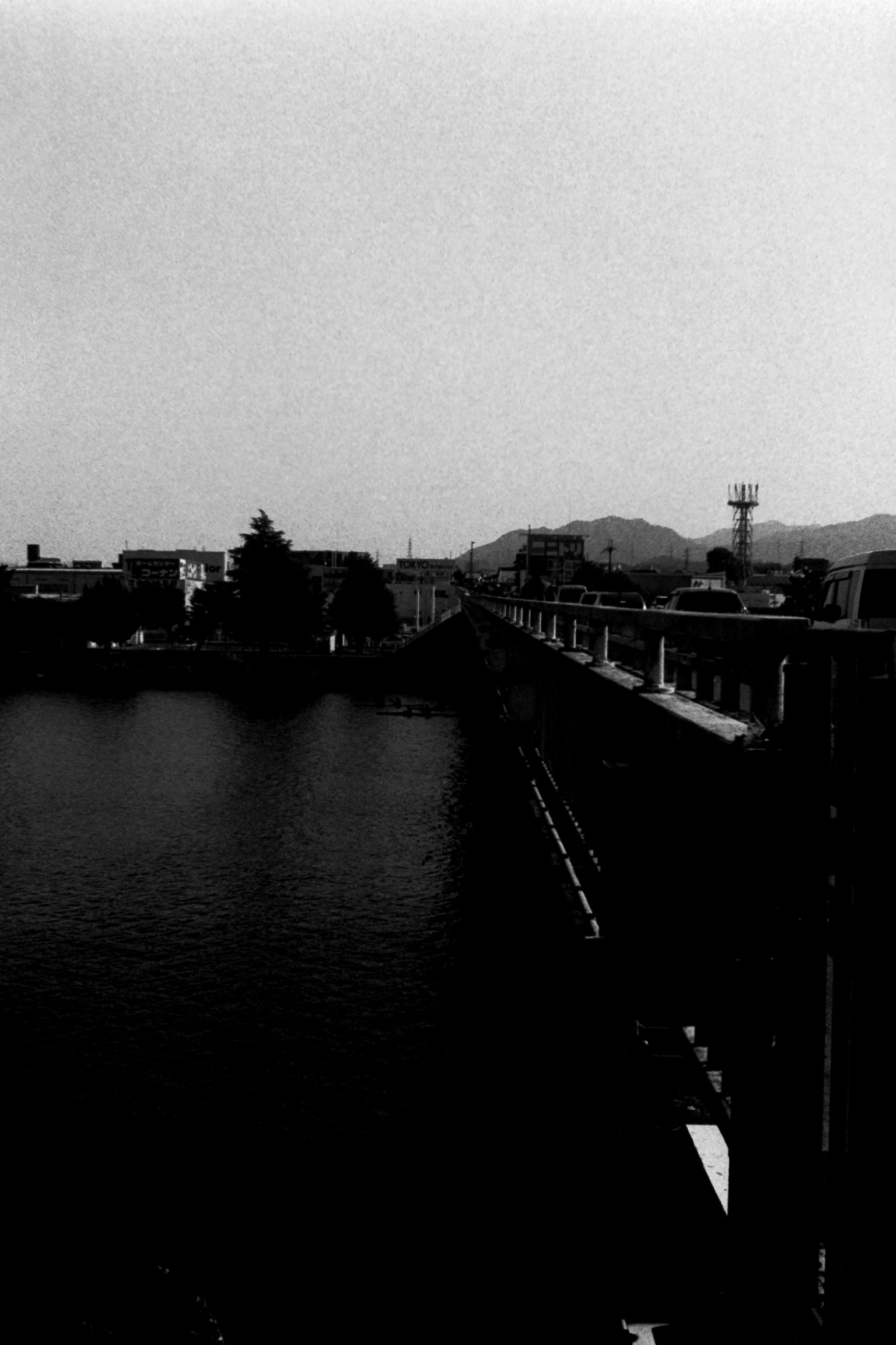 Black and white river scene with a visible bridge