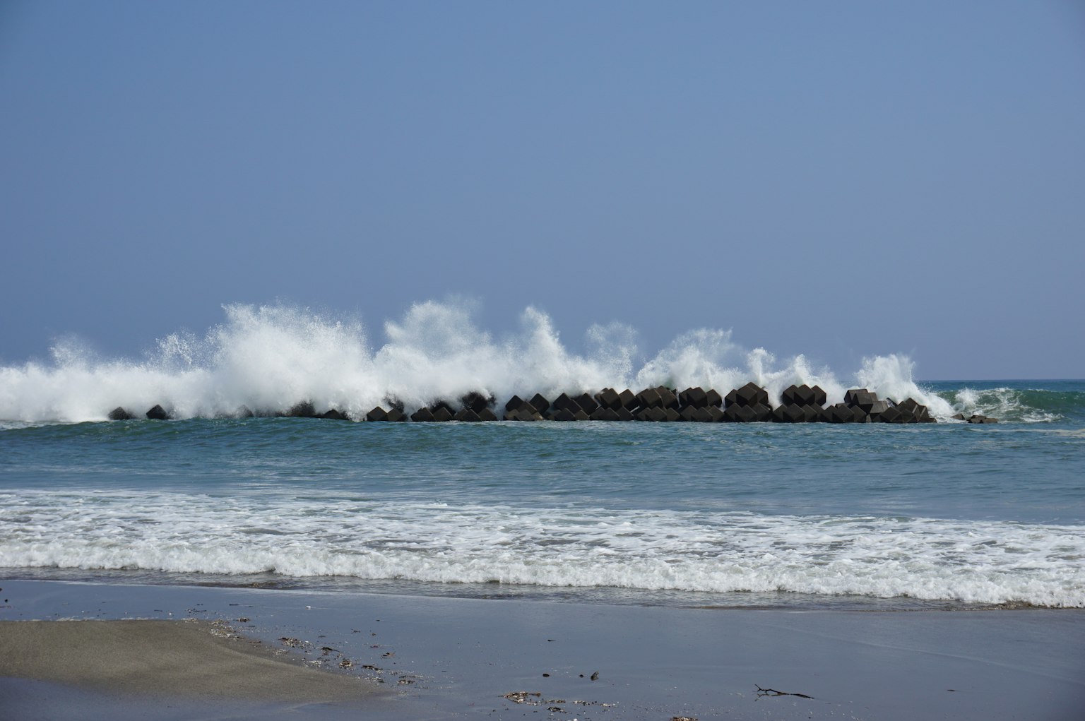 海浪在阳光明媚的沙滩上冲击岩石