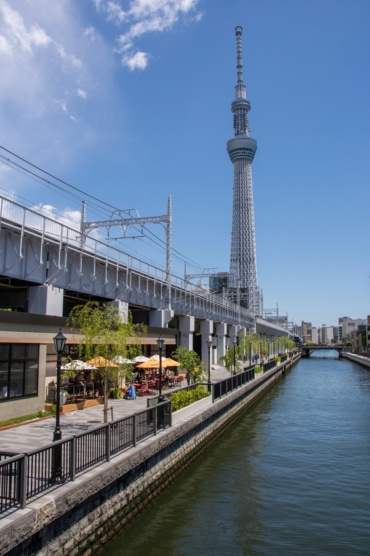 Tokyo Skytree towering over a canal with outdoor cafes