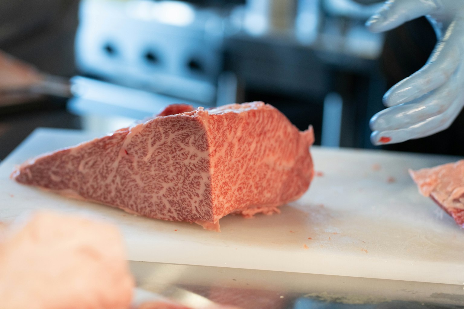 Un morceau de viande persillée en cours de découpe sur une planche à découper blanche
