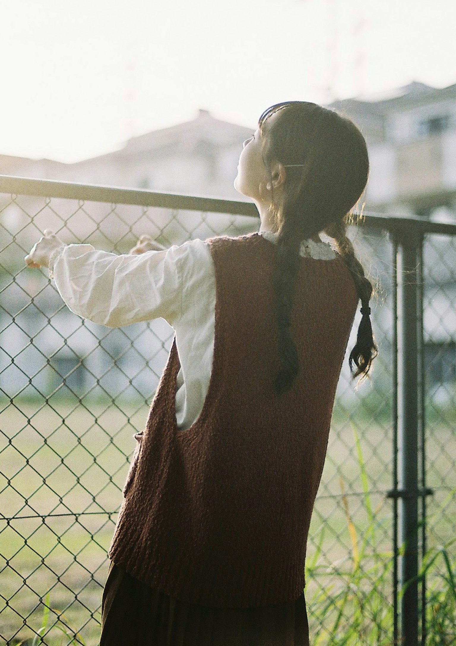 一个女孩靠在栅栏上仰望日落的天空