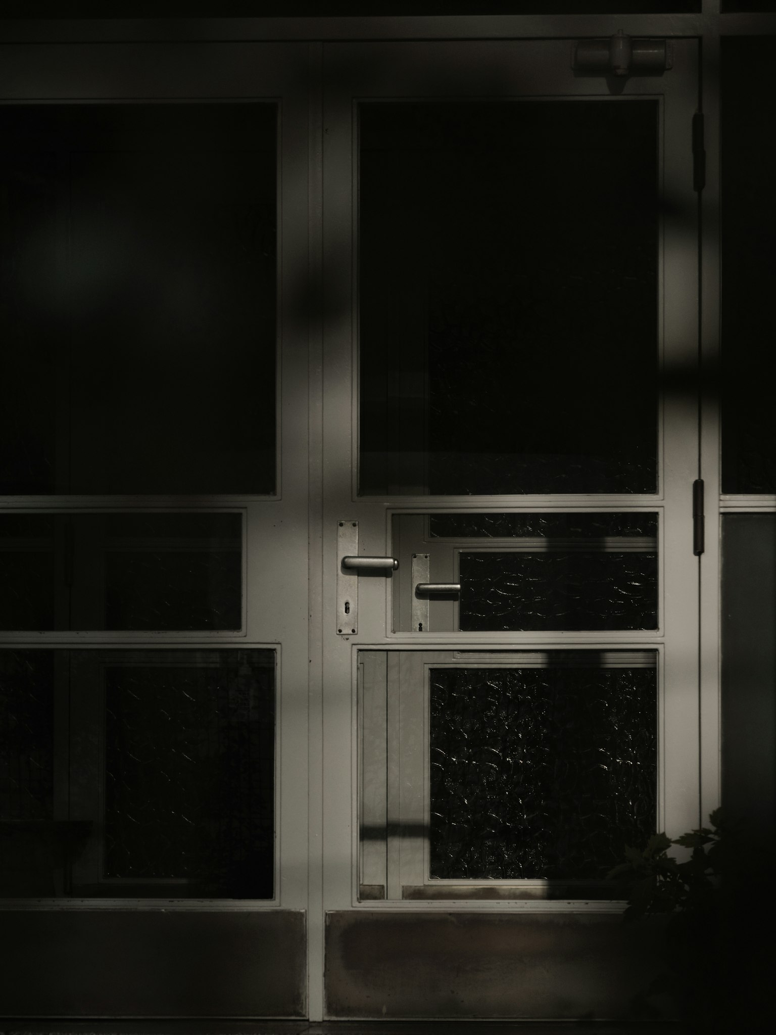 Primo piano di una porta bianca con motivi intricati e ombre