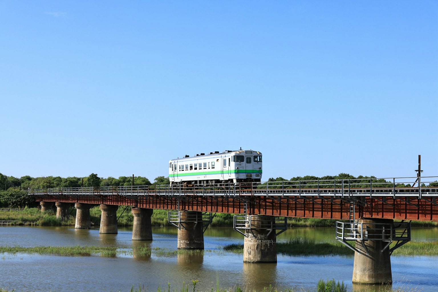 Tren cruzando un puente sobre el agua bajo un cielo azul claro