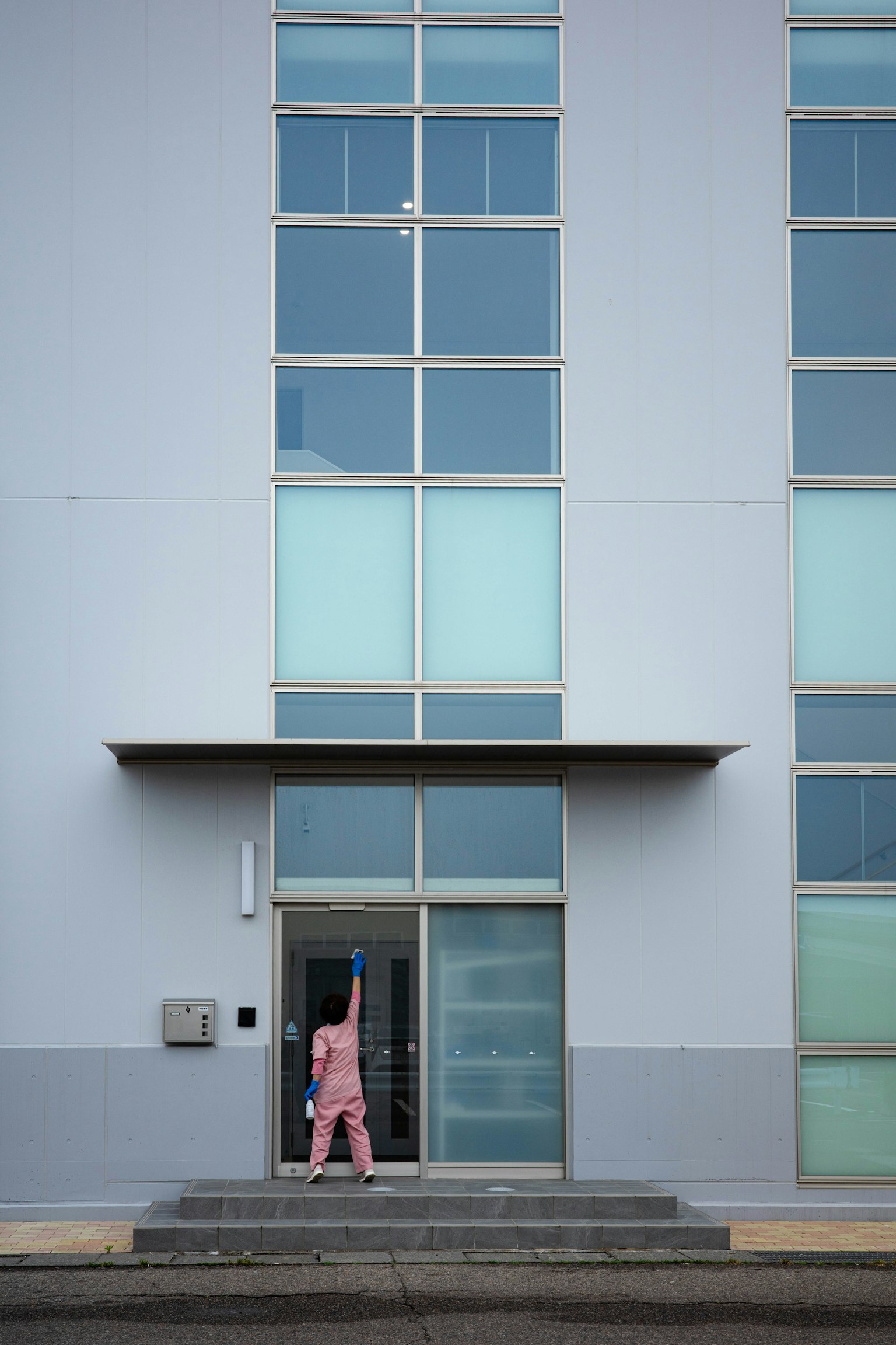 Persona in abbigliamento rosa in piedi davanti a un edificio moderno con facciata blu