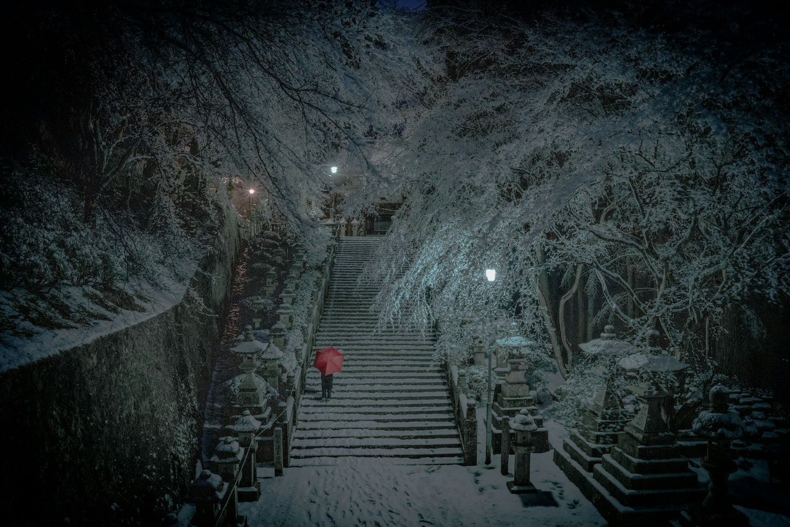 穿著紅色外套的人爬上被雪覆蓋的樓梯的圖像