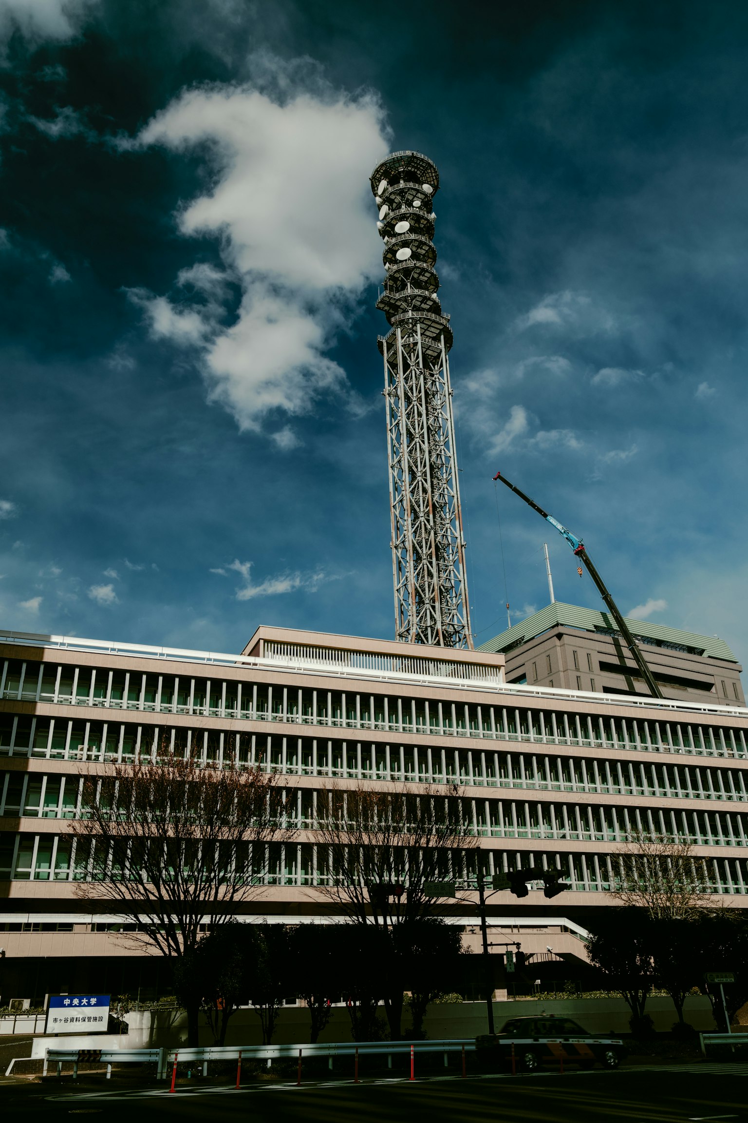 Hoher Kommunikationsturm neben einem Gebäude unter einem blauen Himmel