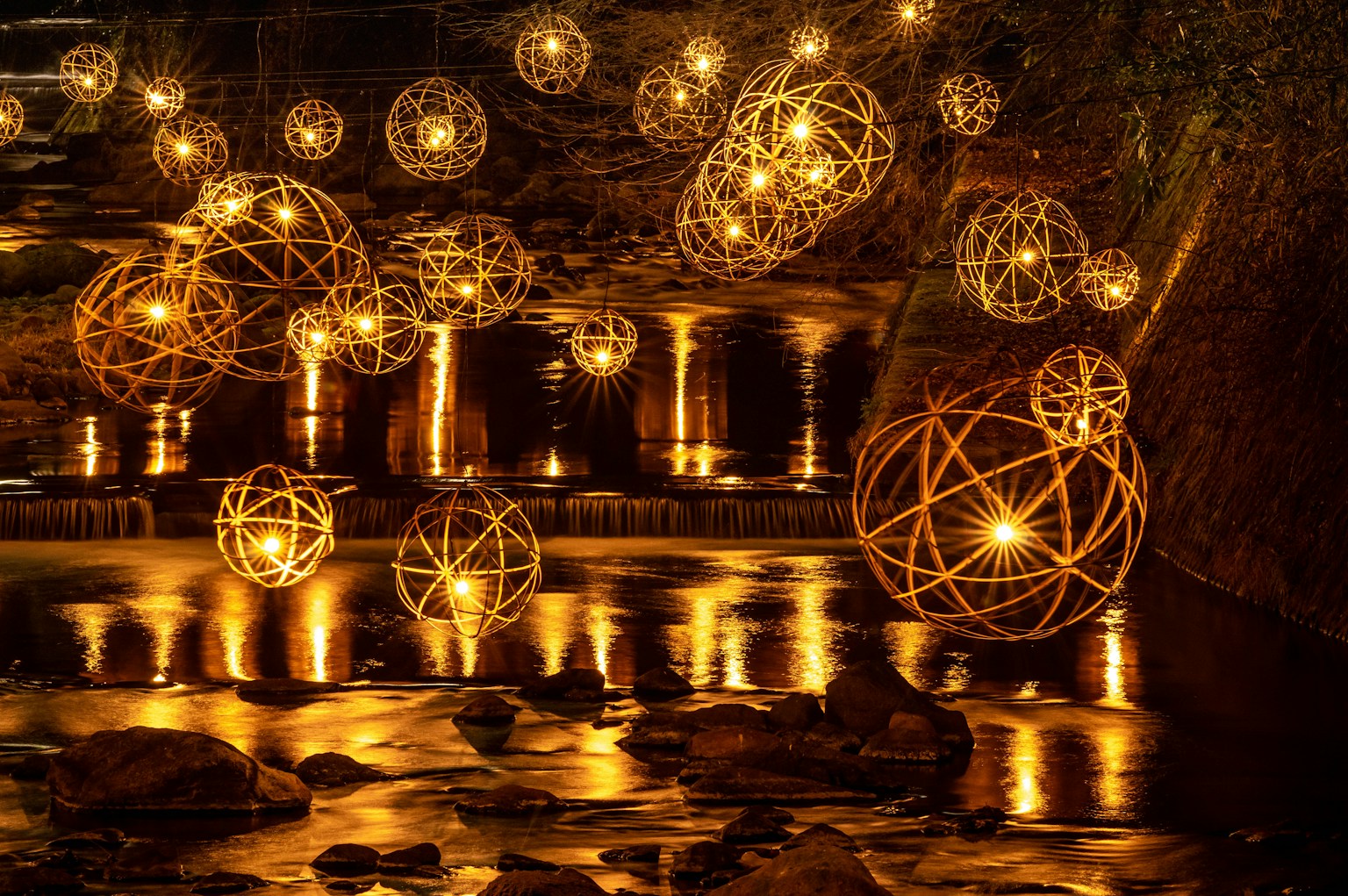 Una scena magica con sfere decorative luminose riflesse sulla superficie dell'acqua e uno sfondo scuro