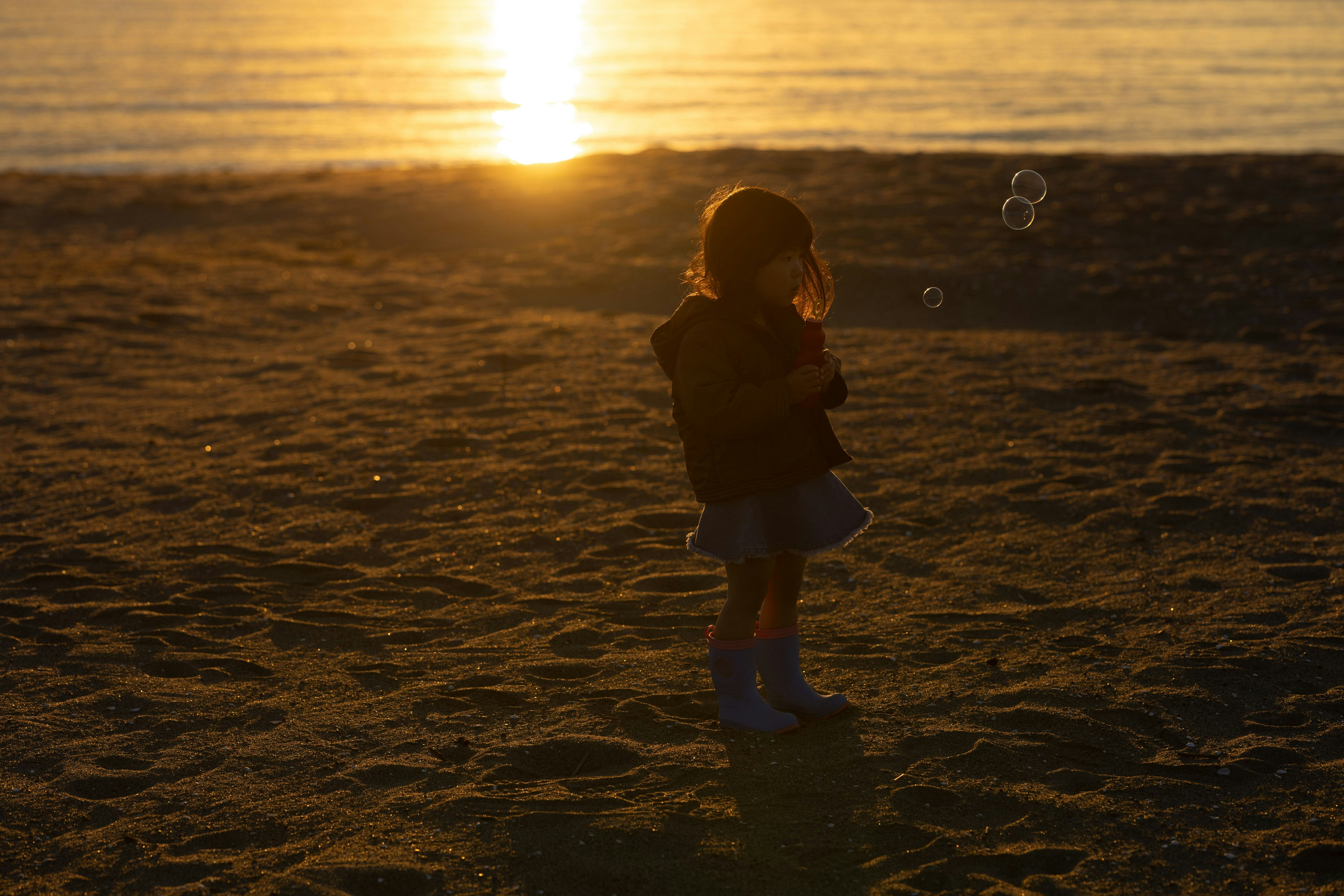 夕日に照らされた海辺で立つ親子のシルエット