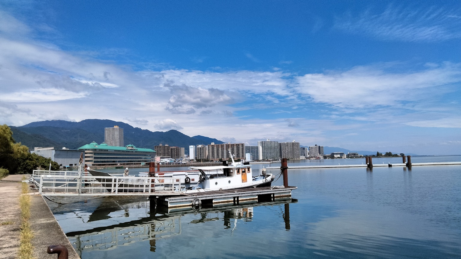 一艘停靠在平静海面上的船，背景是晴朗的蓝天和远处的建筑
