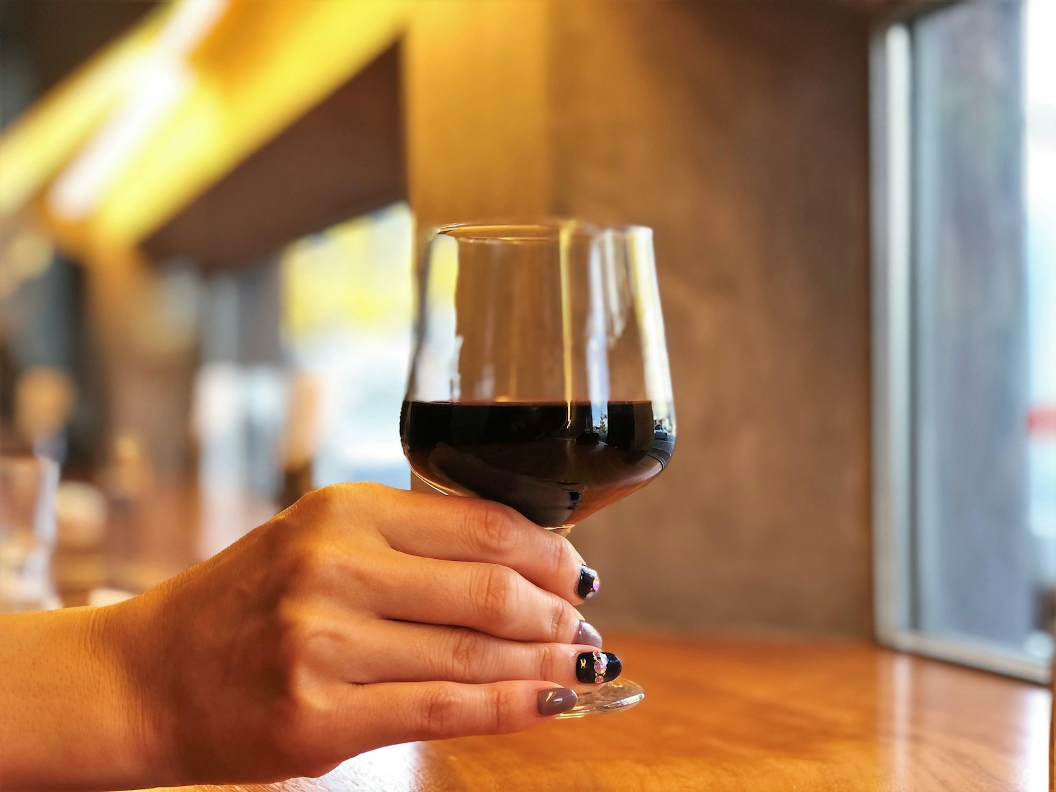 A hand holding a glass of red wine
