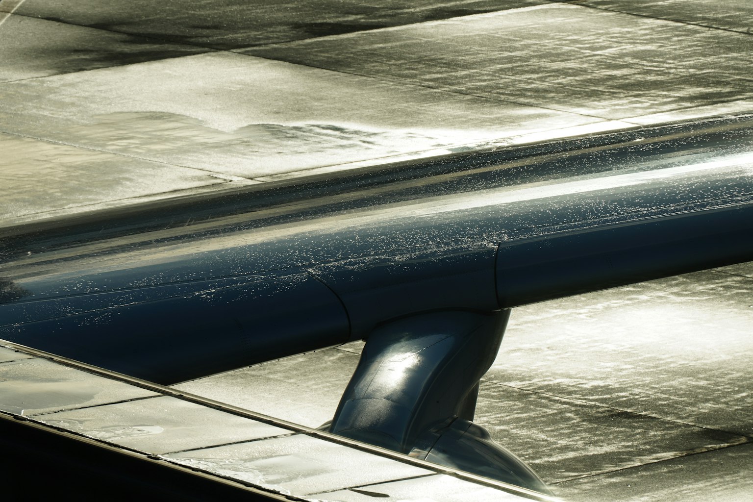 Gros plan d'une aile d'avion avec des gouttes sur une surface métallique