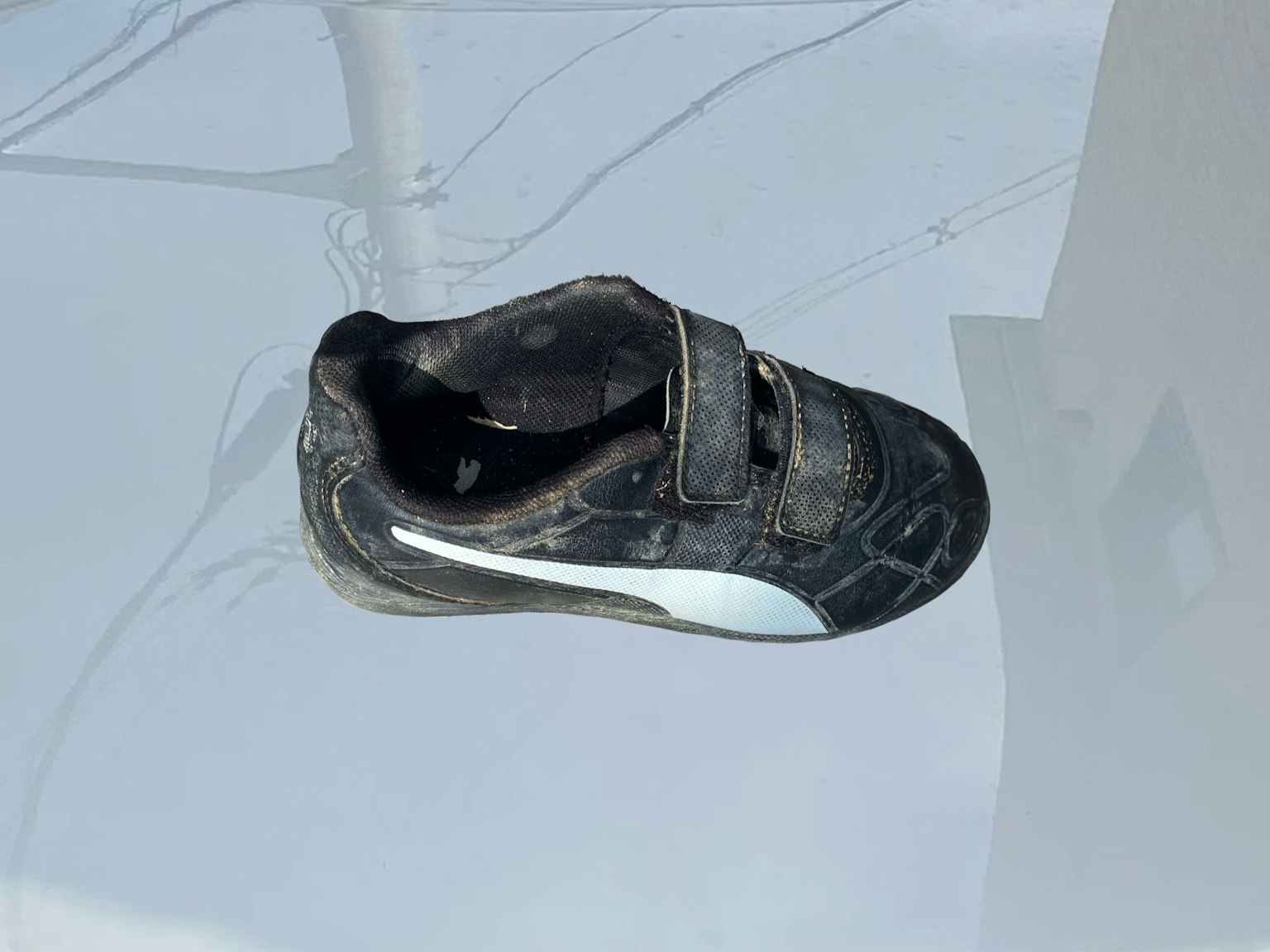 Sepatu hitam dengan aksen putih di permukaan reflektif