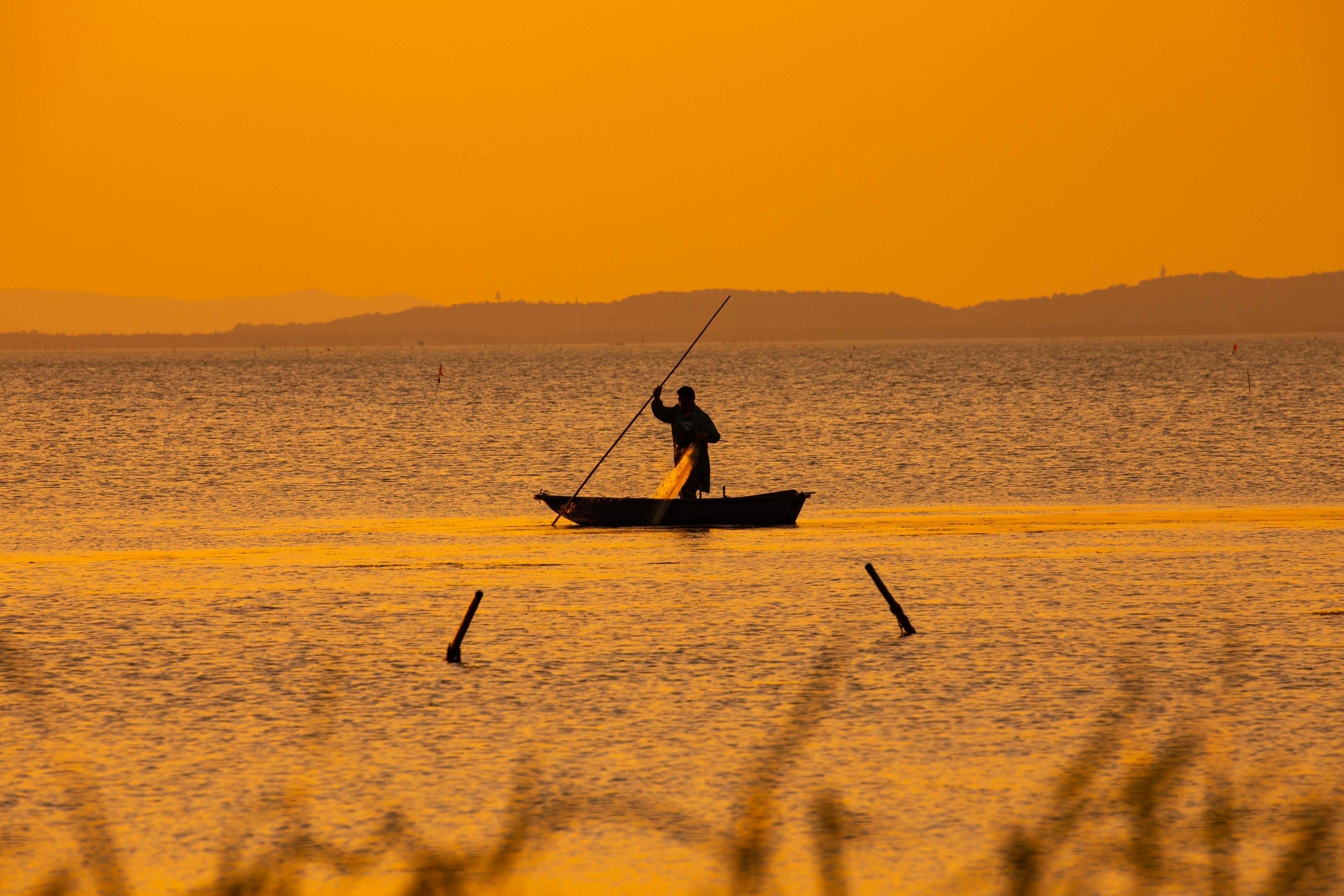 夕日に照らされた海上のカヤックに乗る人物
