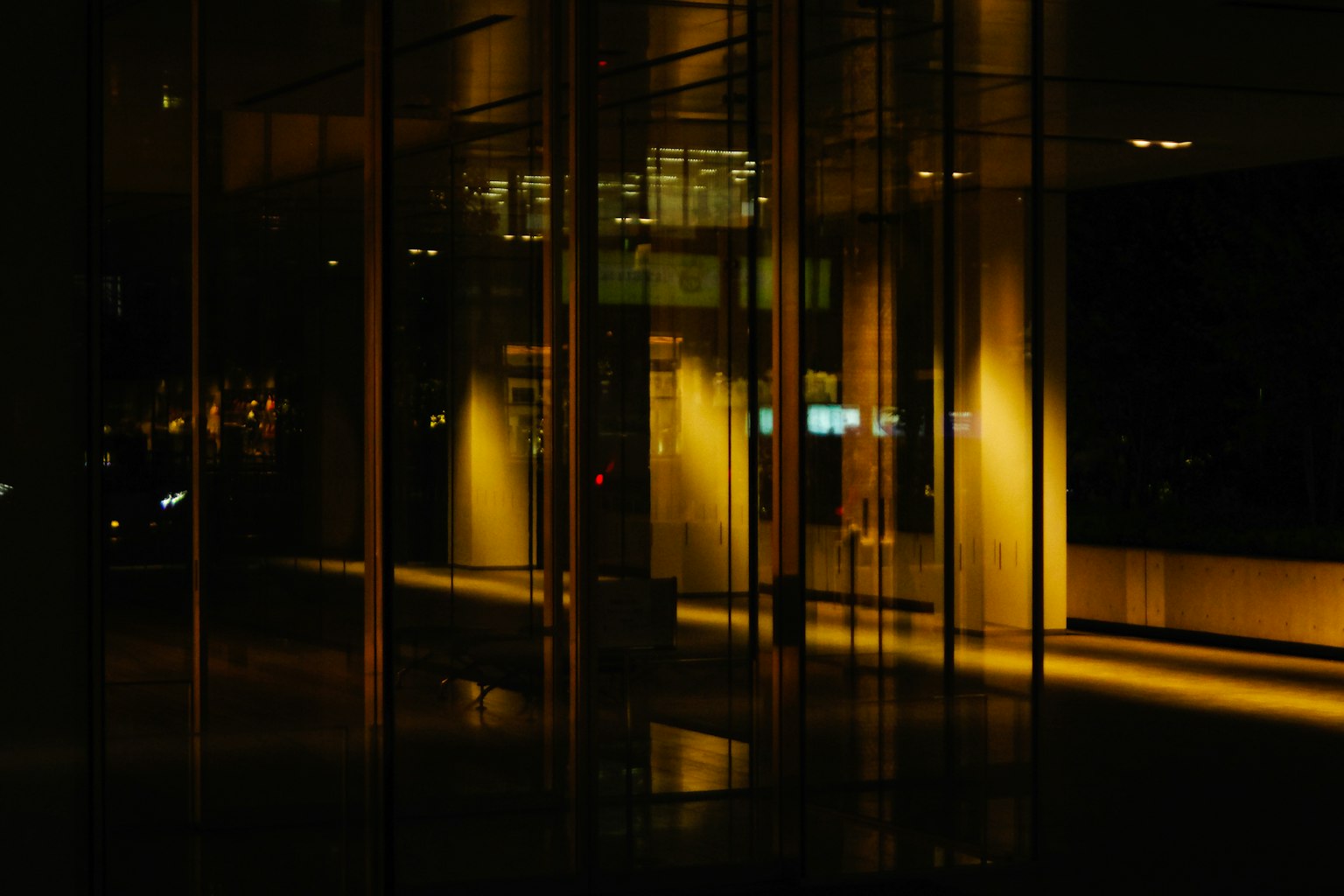 Ein Raum mit Glaswänden und warmem Licht in einer dunklen Umgebung