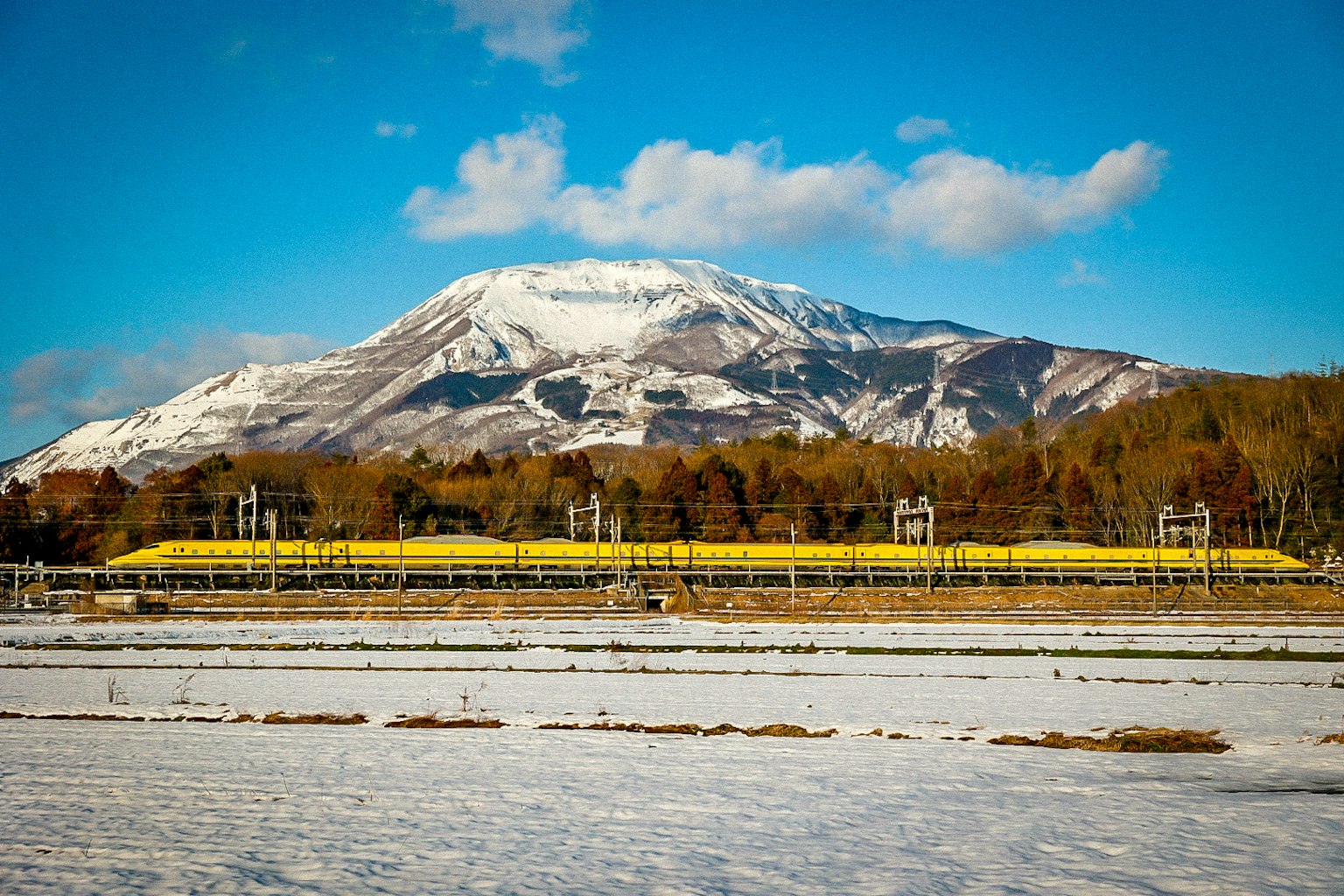 Landschaft mit schneebedeckten Feldern und einem Berg im Hintergrund