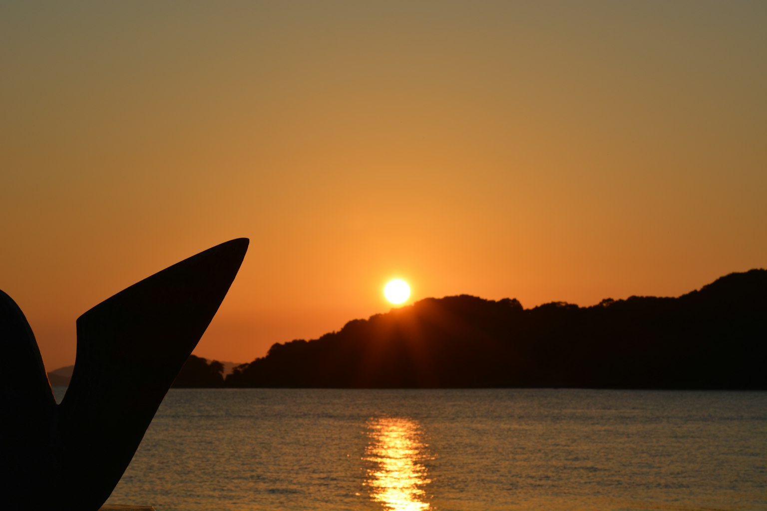 Un paesaggio bellissimo con il sole che tramonta all'orizzonte accanto a una parte di barca