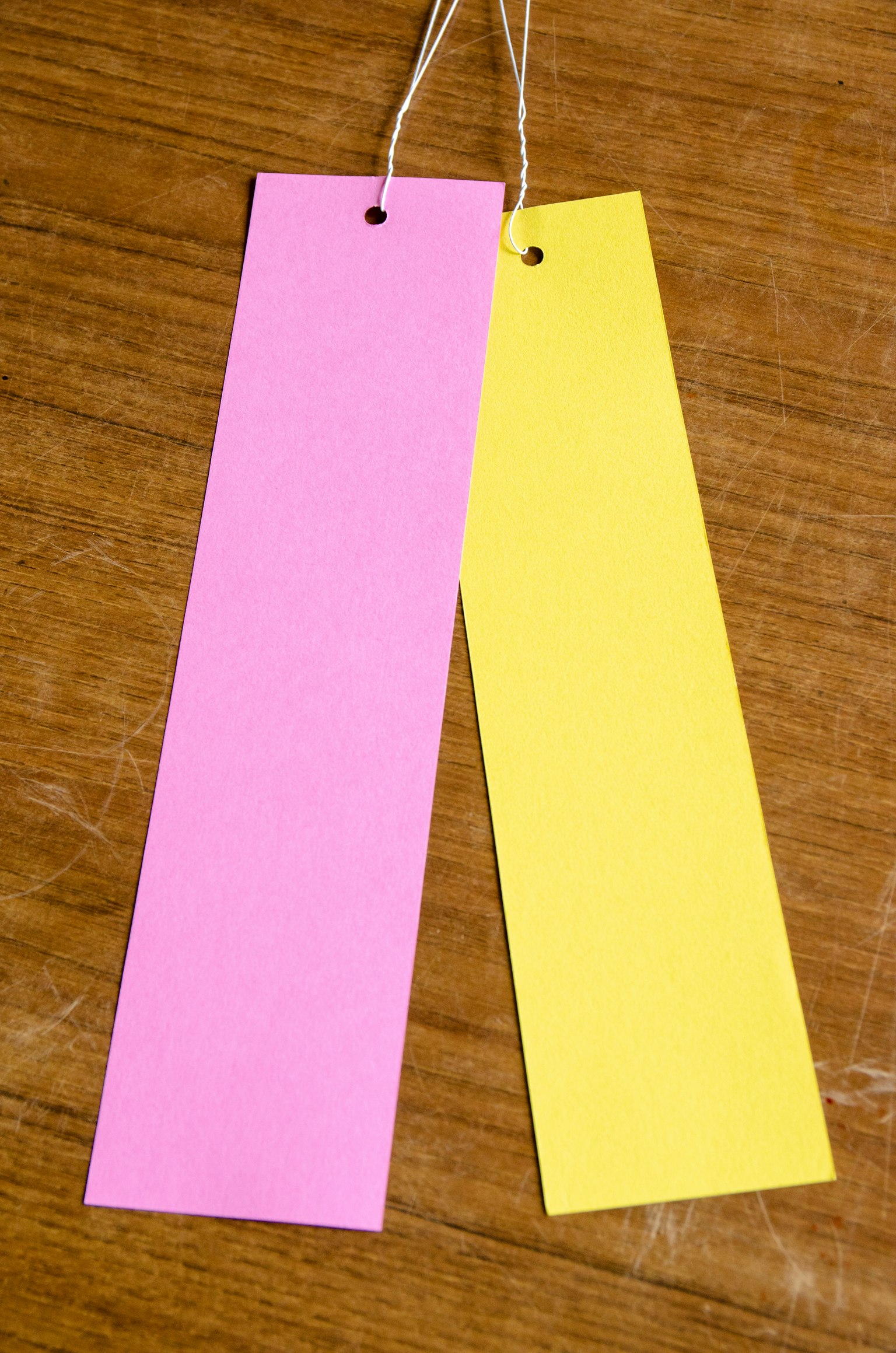 Dos etiquetas una rosa y una amarilla sobre una mesa de madera
