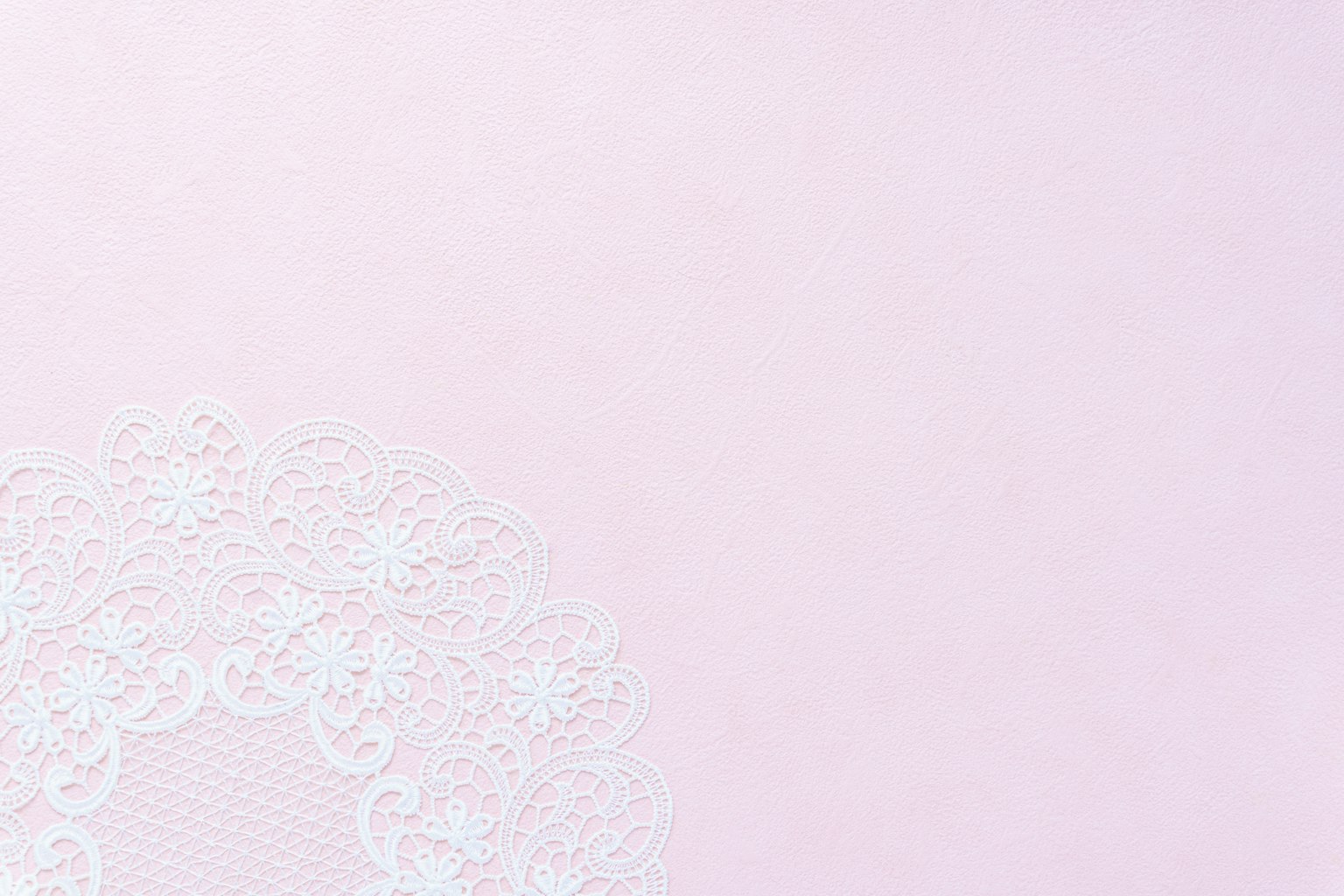 Fondo rosa claro con un patrón de encaje blanco parcialmente visible