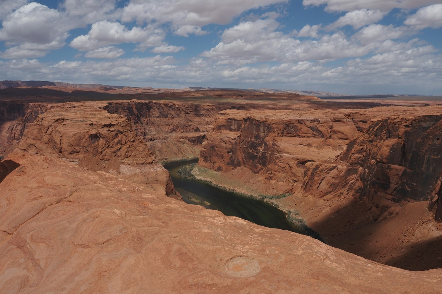 Atemberaubende Aussicht auf Horseshoe Bend mit roten Felsen und einem grünen Fluss unter einem blauen Himmel