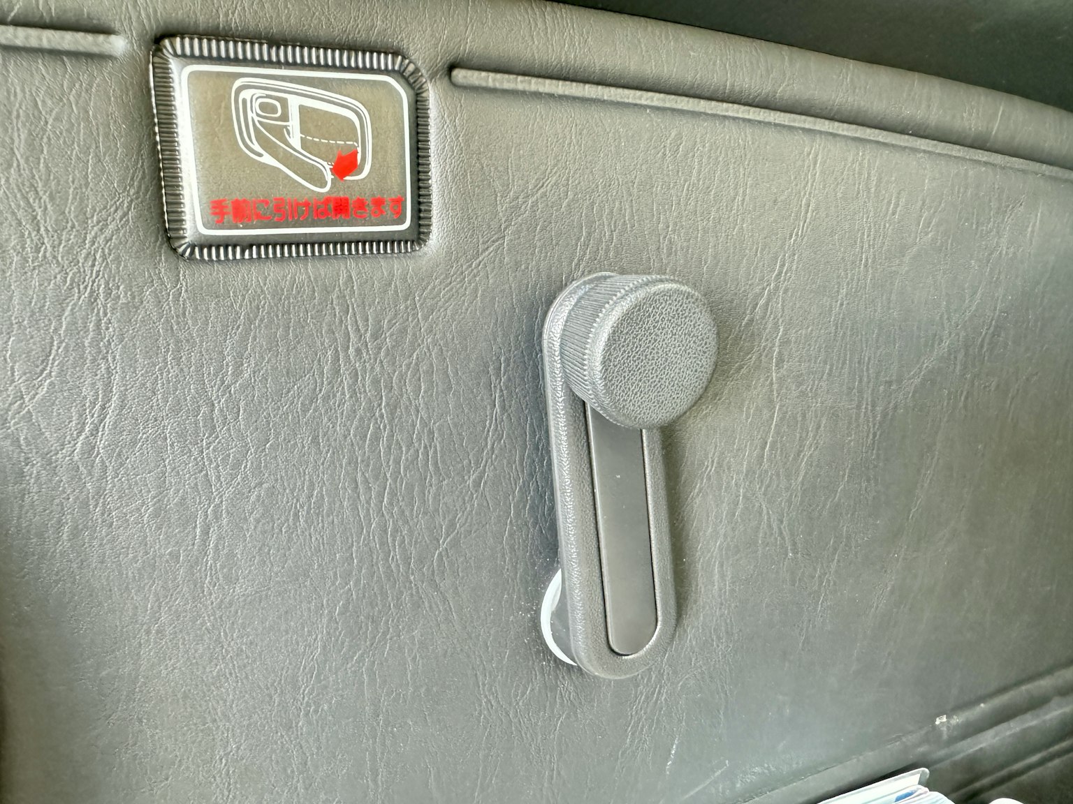 Image of a gray plastic panel and seat adjustment lever on a car door interior
