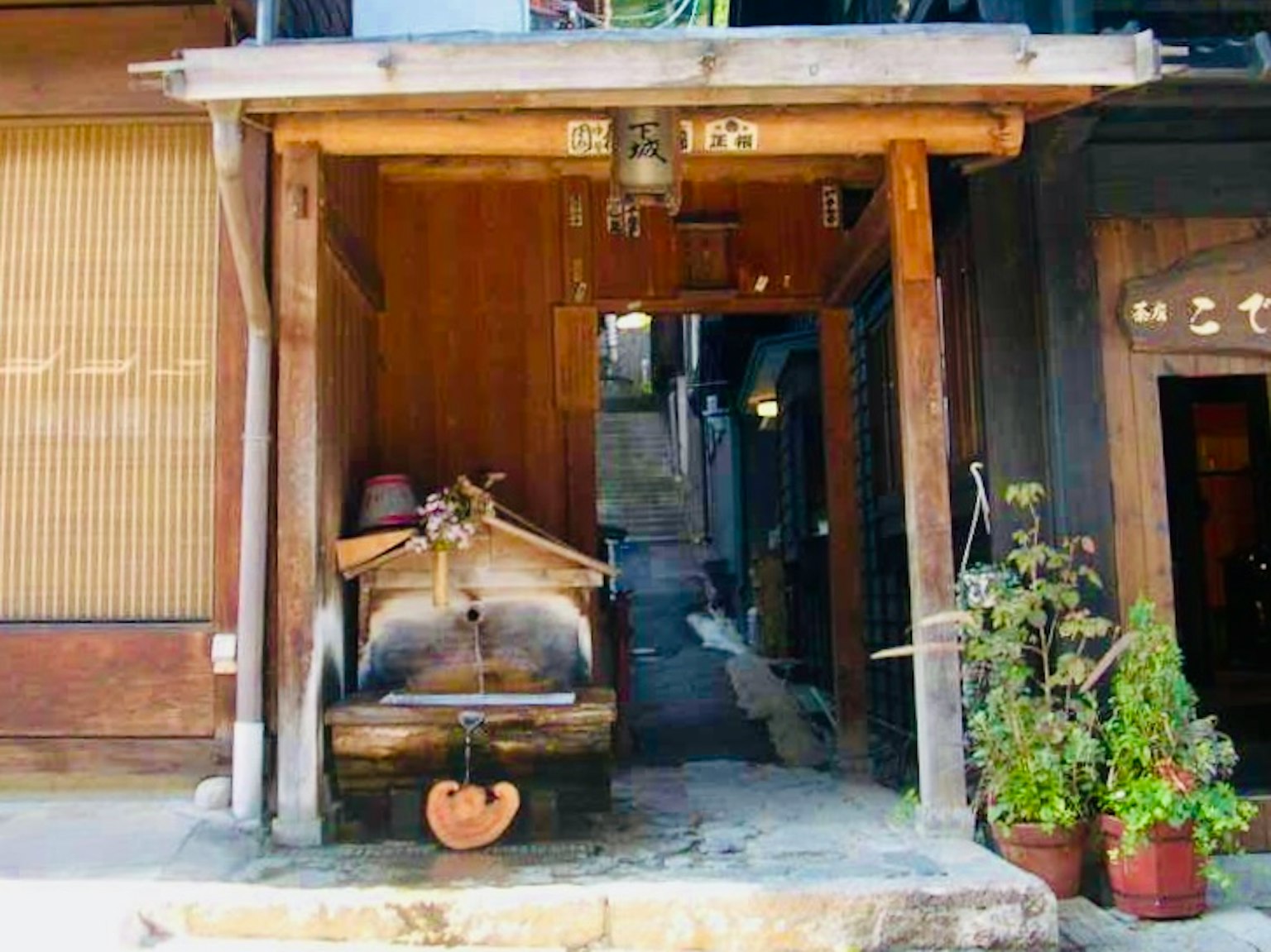 Entrée d'une structure en bois avec une roue à eau et des plantes en pot