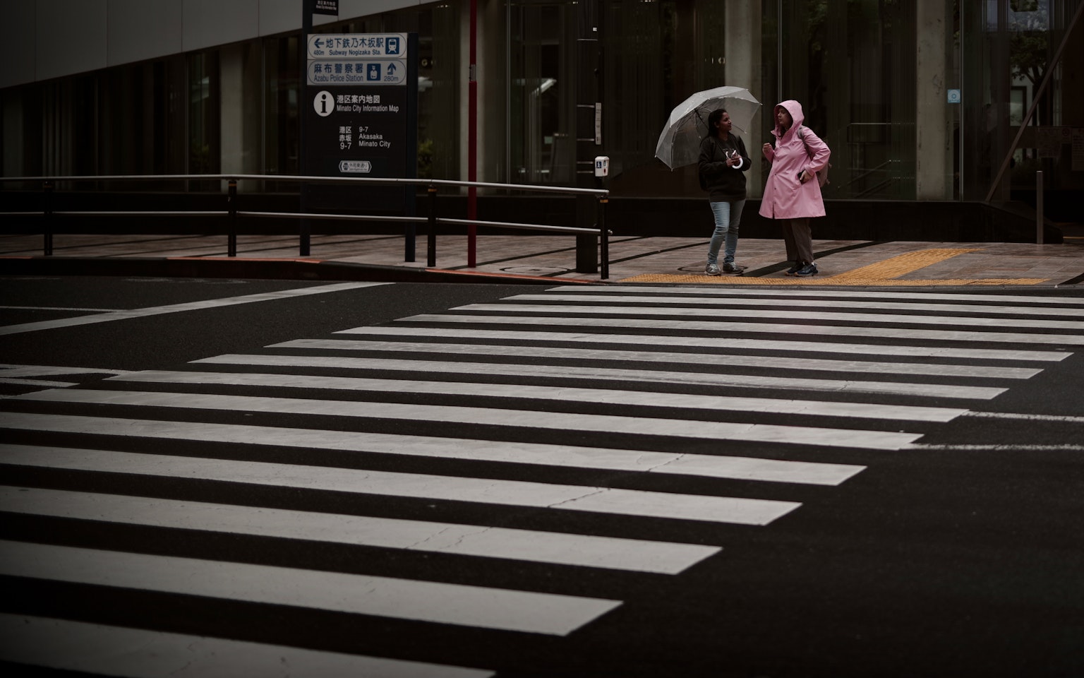 两位女性正在过马路，一位穿着粉色外套，城市雨天场景