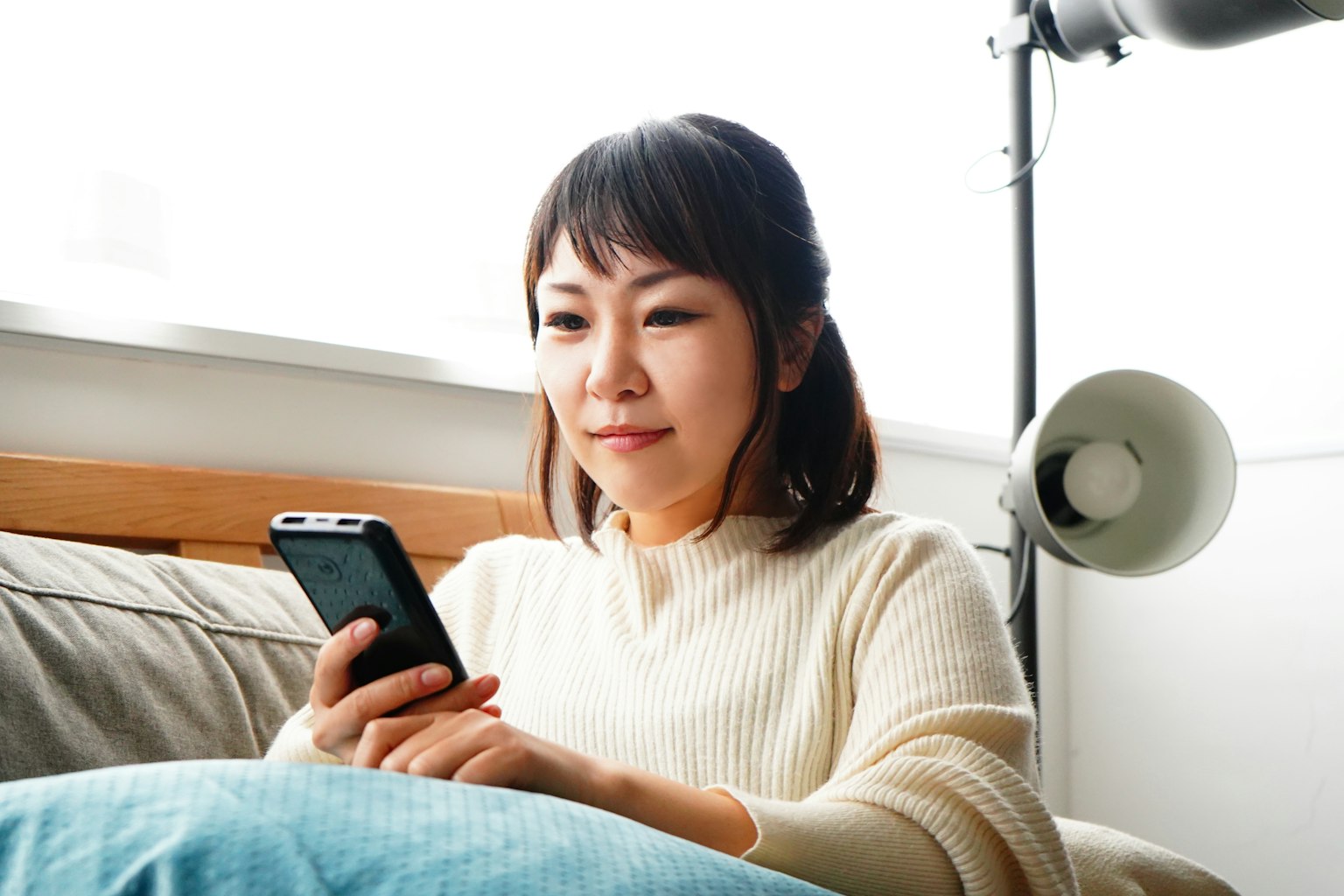 Eine Frau sitzt auf einem Sofa und schaut auf ihr Smartphone