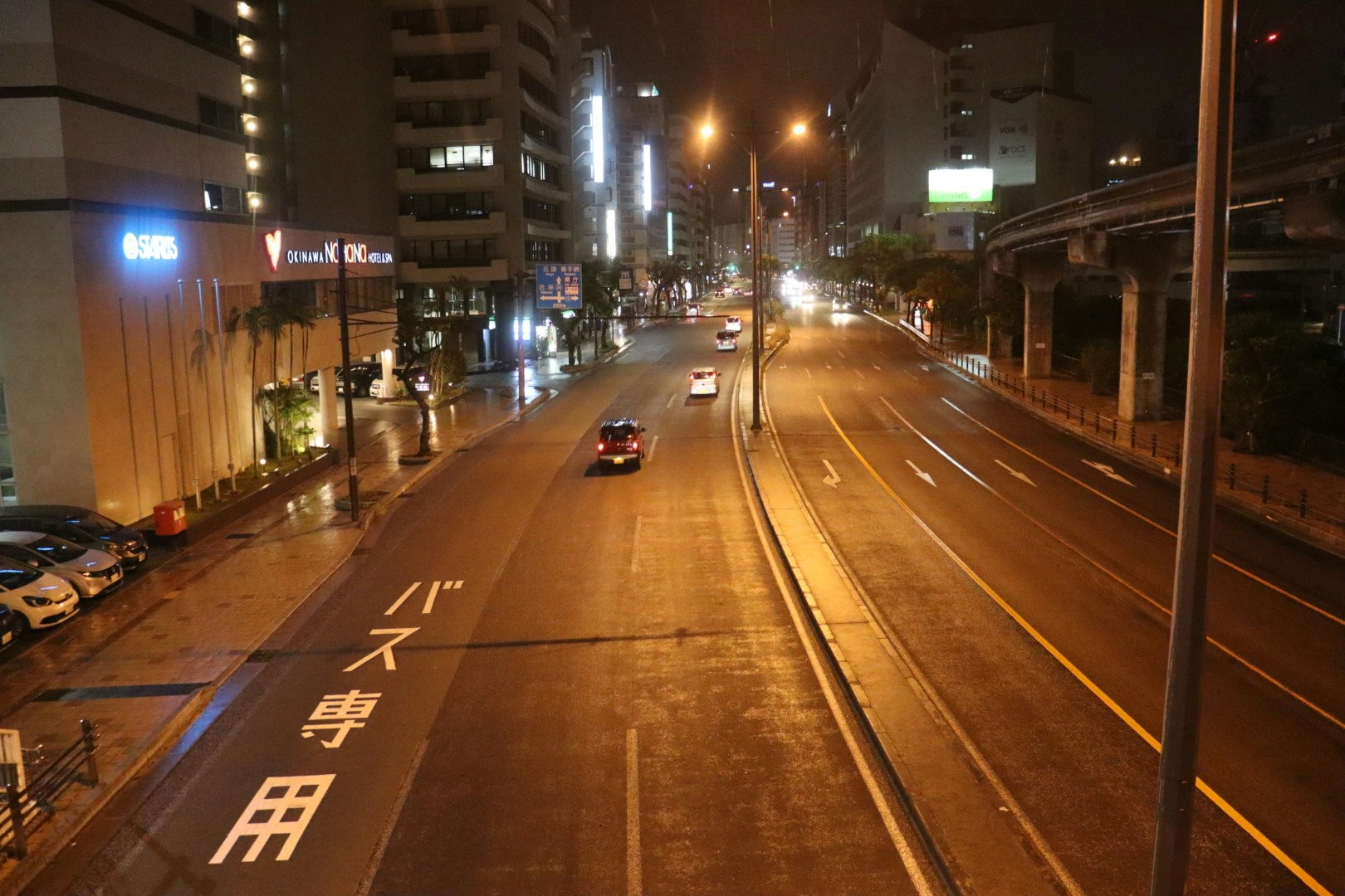 夜の交差点を走る車とバスのある沖縄の道路