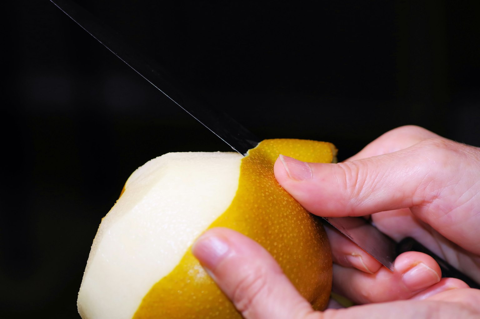 Una persona che sbuccia una pera con un coltello