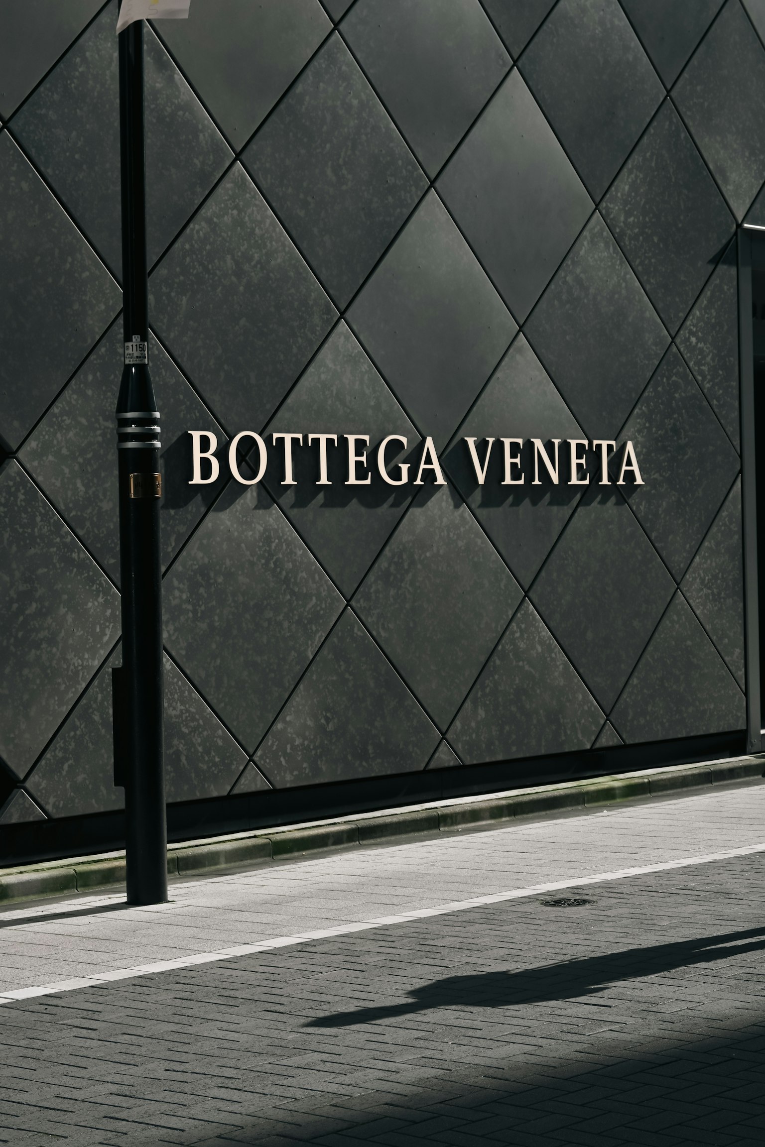 Vitrina con el logo de Bottega Veneta en una pared oscura y texturizada
