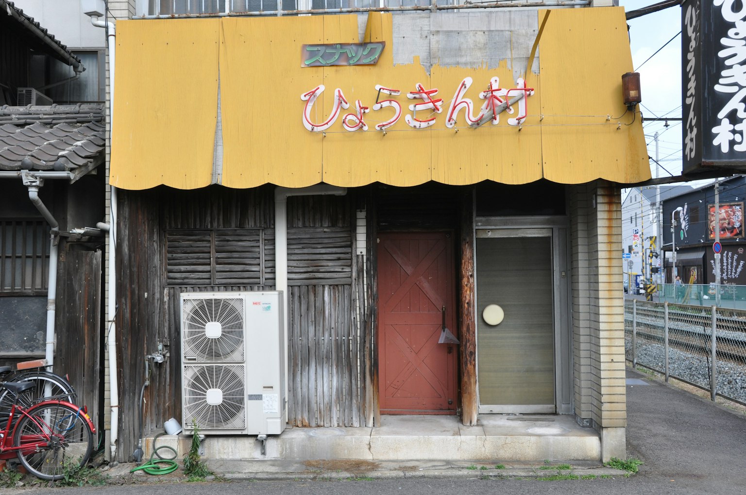 Extérieur d'un vieux magasin avec un auvent jaune et un panneau en hiragana