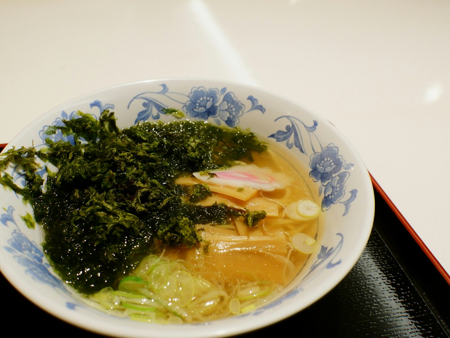 Mangkuk ramen yang indah dengan rumput laut dalam piring berbunga biru