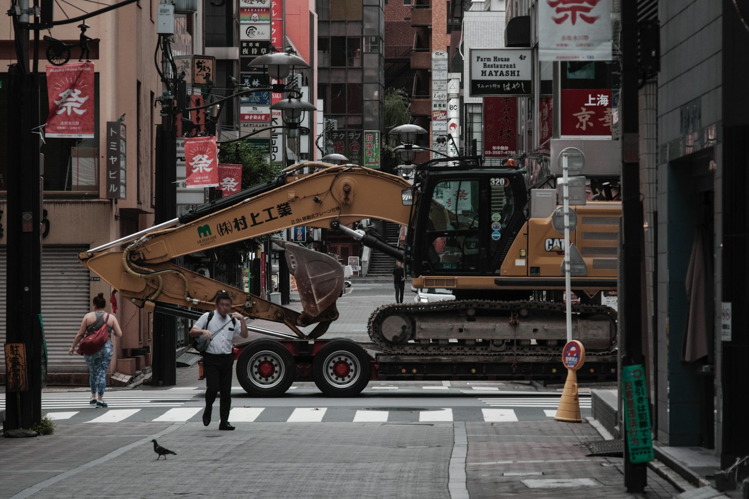 เครื่องจักรก่อสร้างขนาดใหญ่ที่สี่แยกในเมืองพร้อมคนเดินถนน