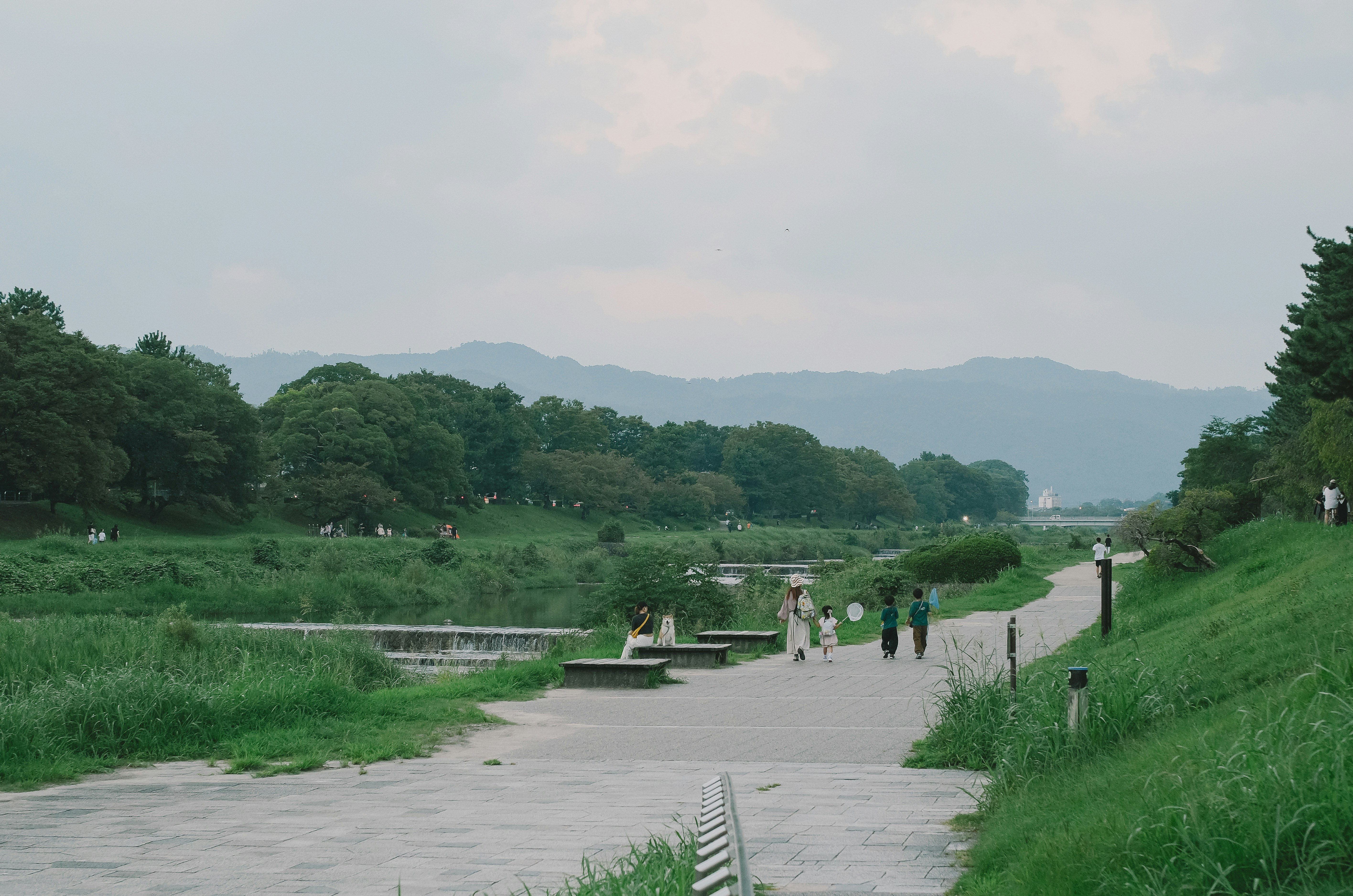 riverside walkway with green lawns and distant mountains