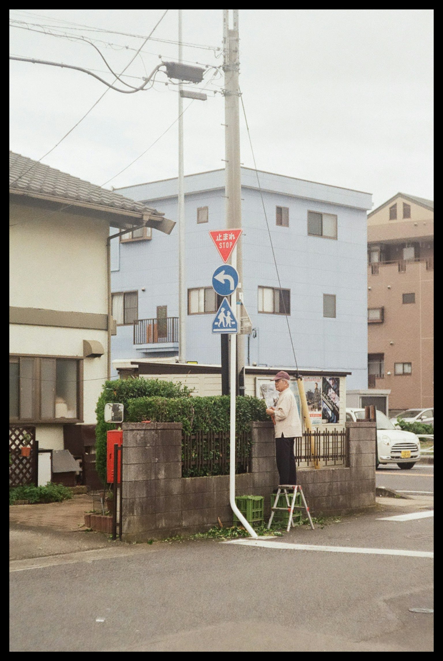 街角で標識を修理している男性と周囲の住宅