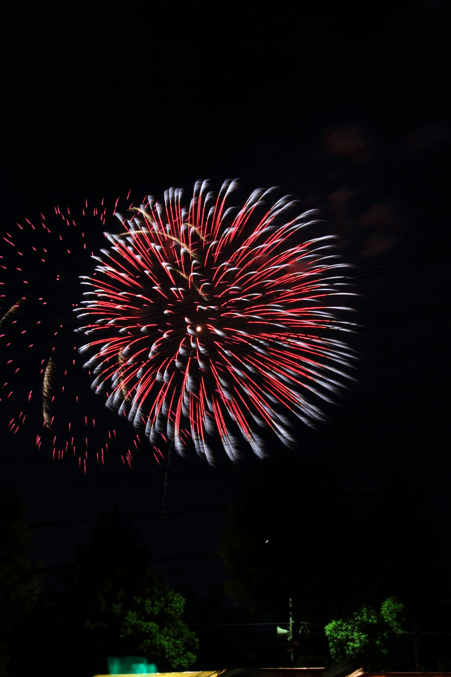 Fuegos artificiales estallando en el cielo nocturno con colores rojos y blancos