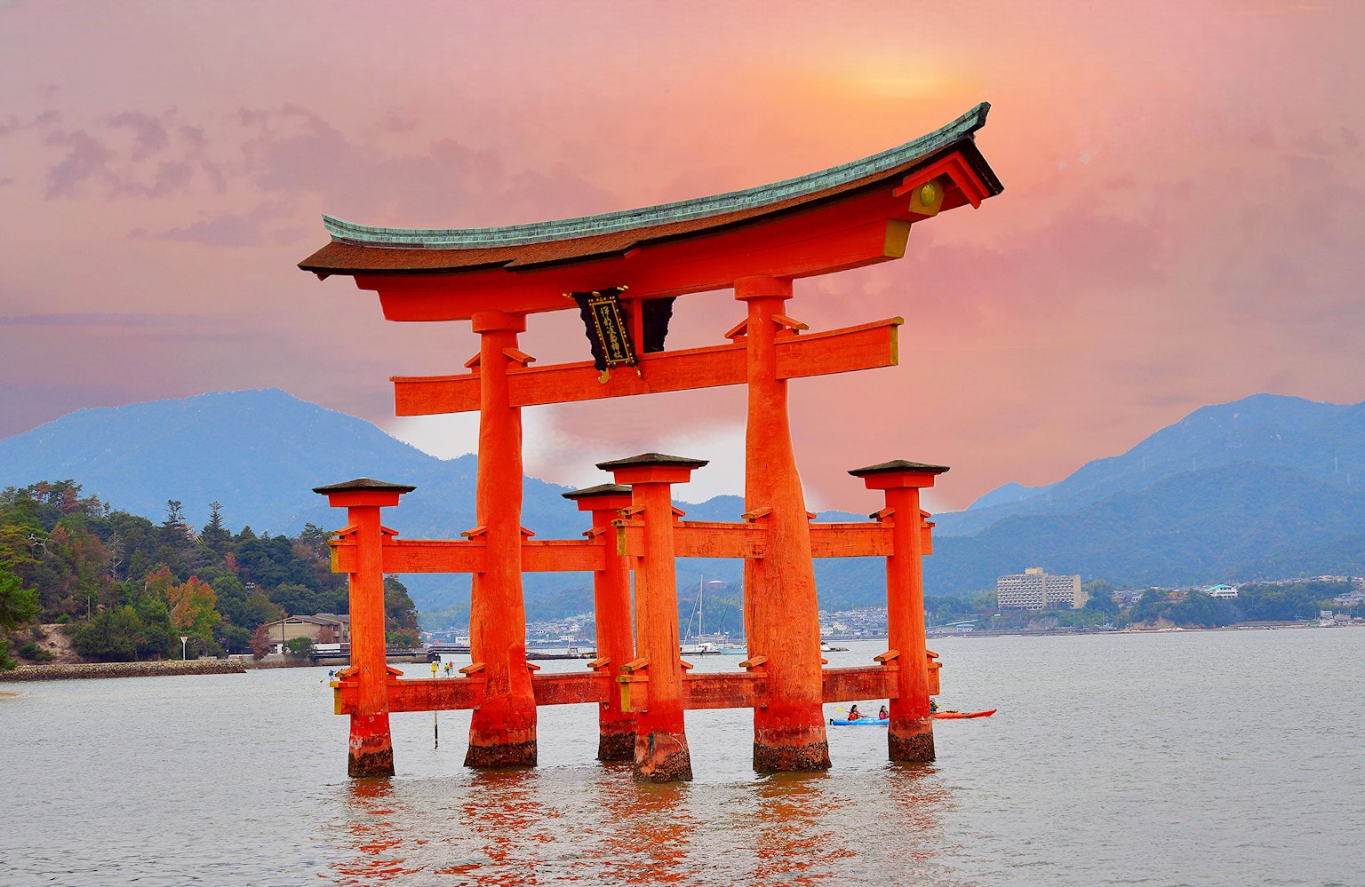 Cổng torii của đền Itsukushima đứng trong nước vào lúc hoàng hôn