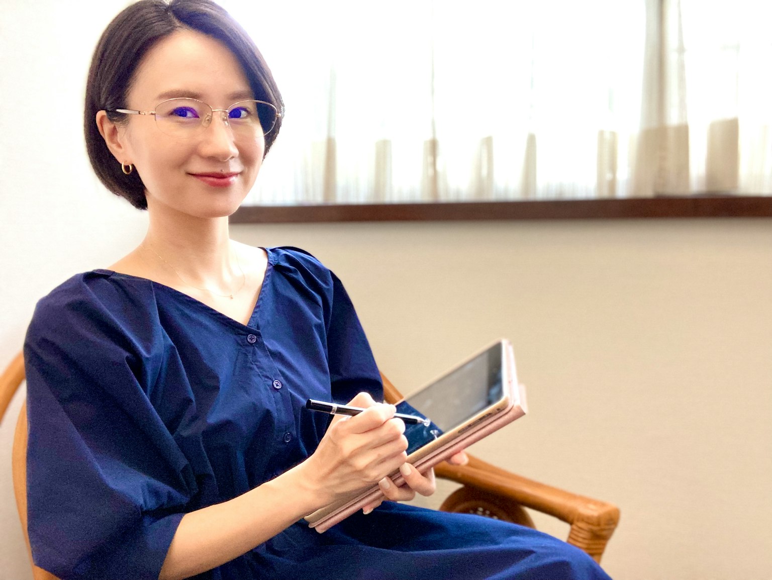 파란 드레스를 입고 태블릿을 들고 미소 짓고 있는 여성의 실내 사진